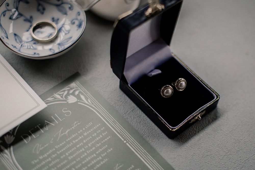 A collection of wedding details including rings, invitations, and decorative elements arranged in a romantic gray color scheme.