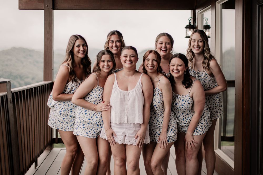 A group wearing matching floral bridesmaid dresses poses together in a hallway for wedding photos.