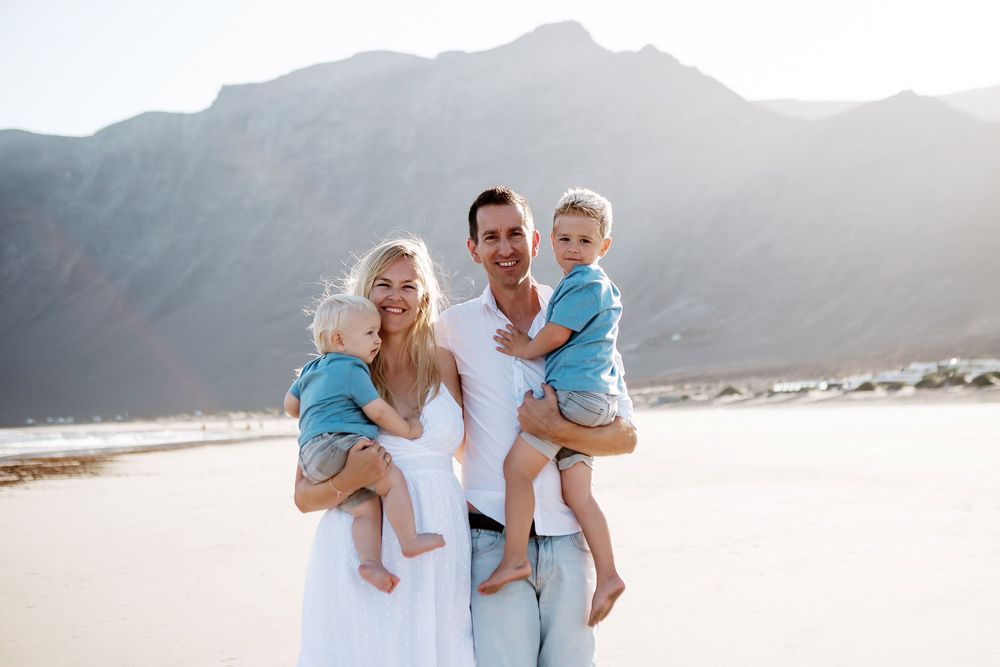 Young family with two children posing against the cliffs of Famara beach - Lanzarote family photography