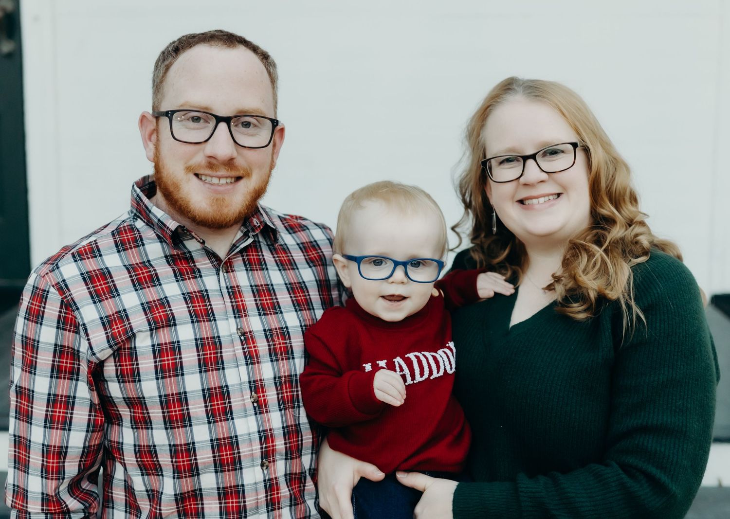Family of three in winter attire posing for holiday portrait.