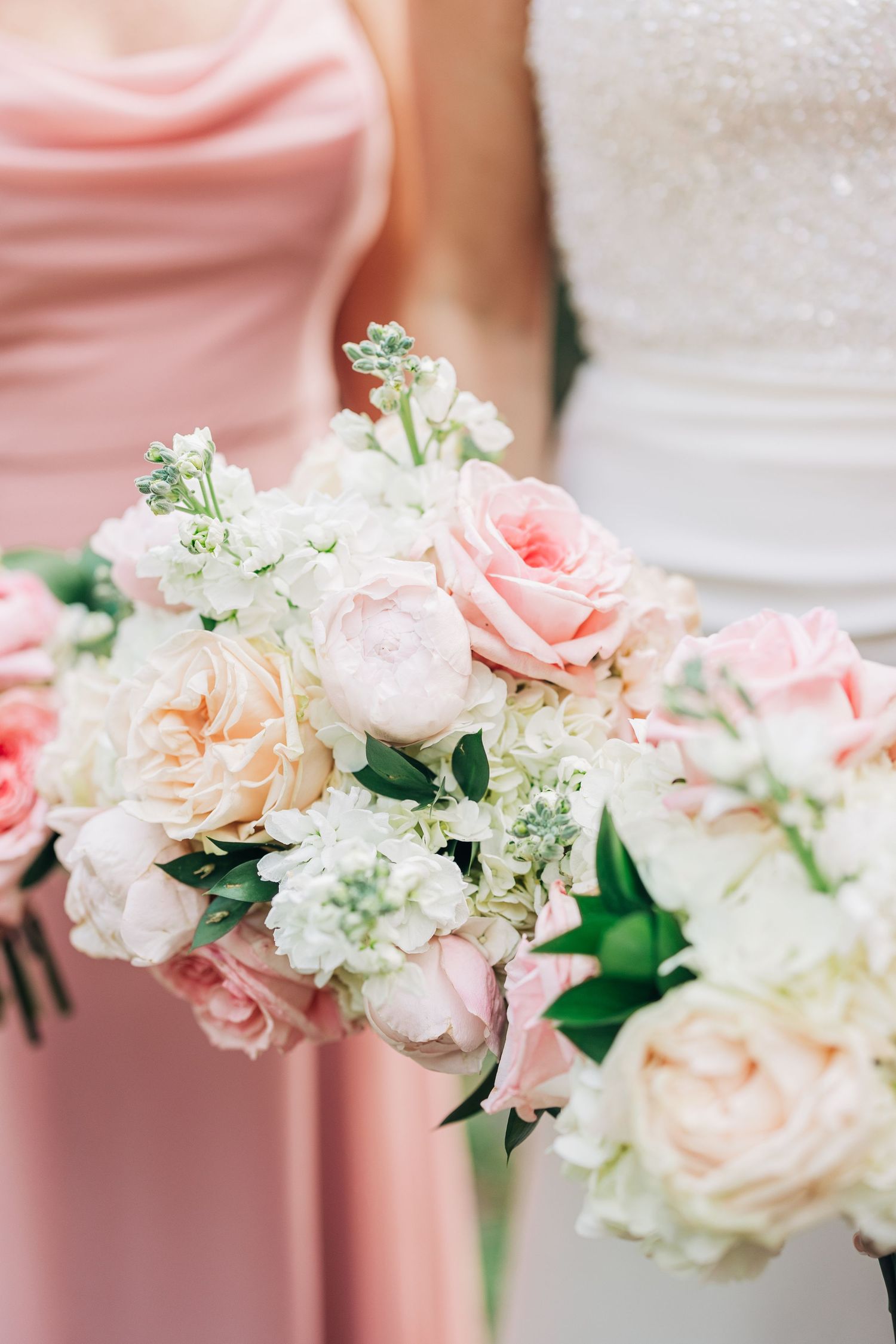 Elegant bridal bouquet featuring soft pink and white roses with delicate baby's breath against blush and white dresses at The Wildflower 301