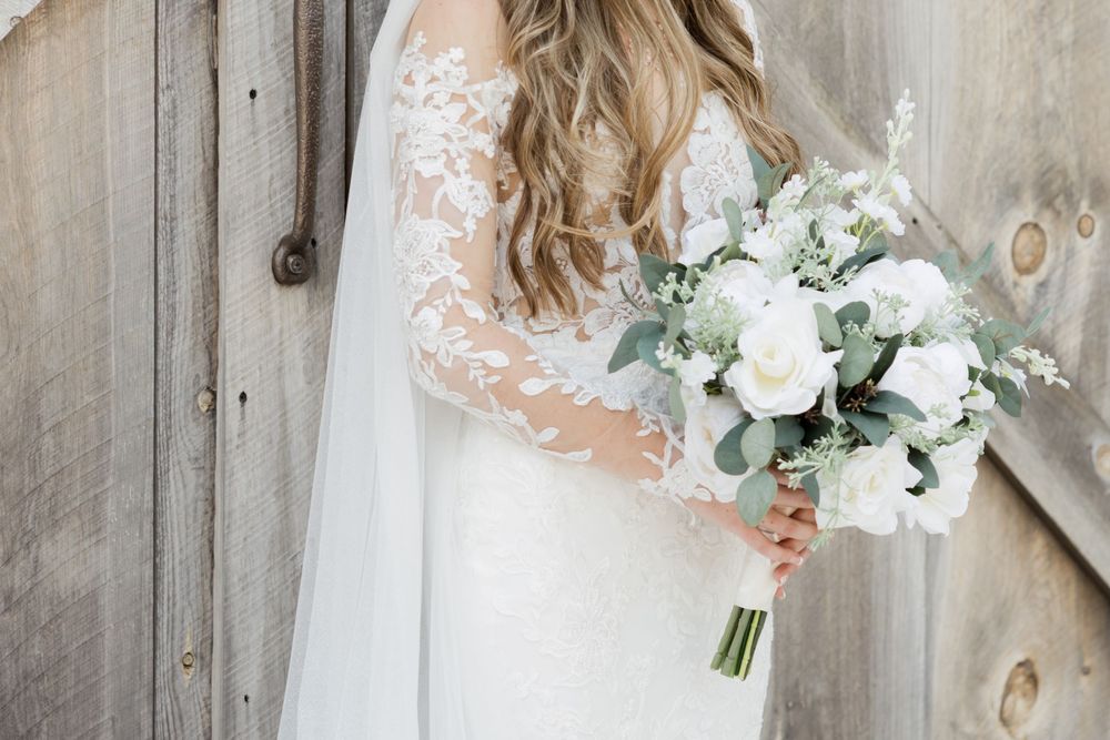 Elegant lace wedding dress with long train photographed in rustic barn setting.