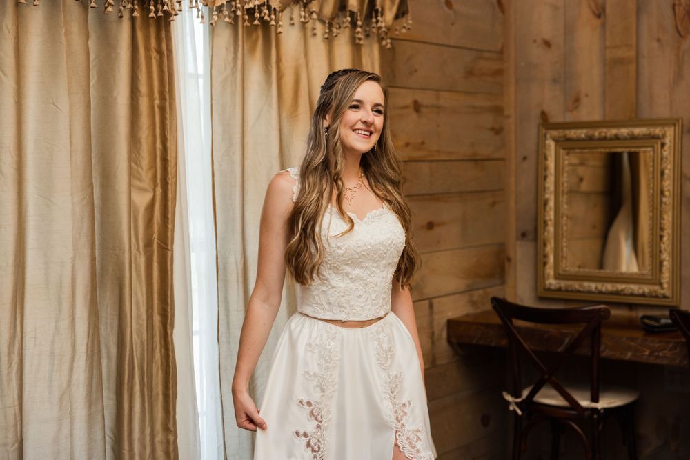 Elegant white lace wedding dress displayed in rustic barn setting with natural lighting.