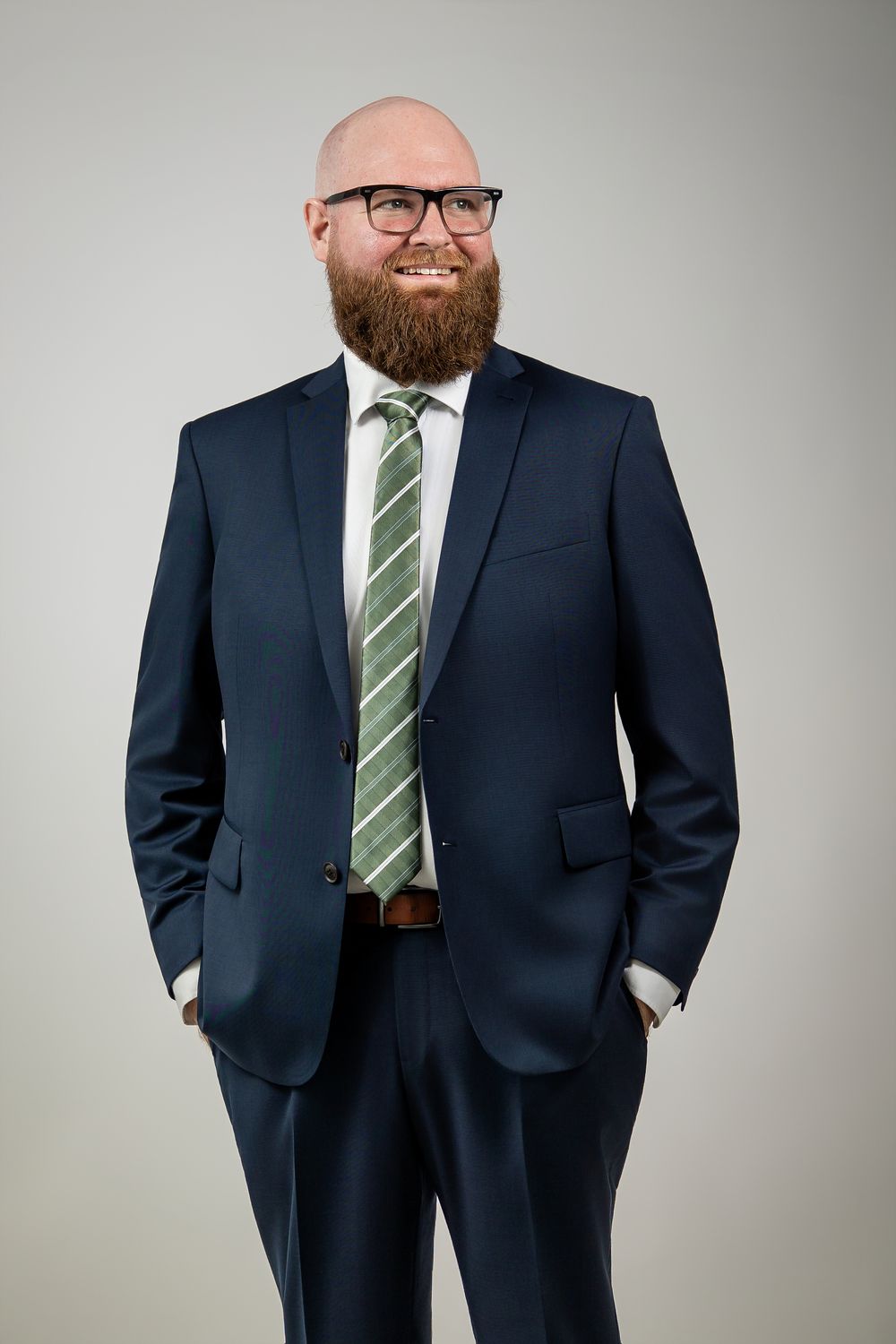 Professional wearing a navy suit and striped tie poses in multiple business portraits against a light background.