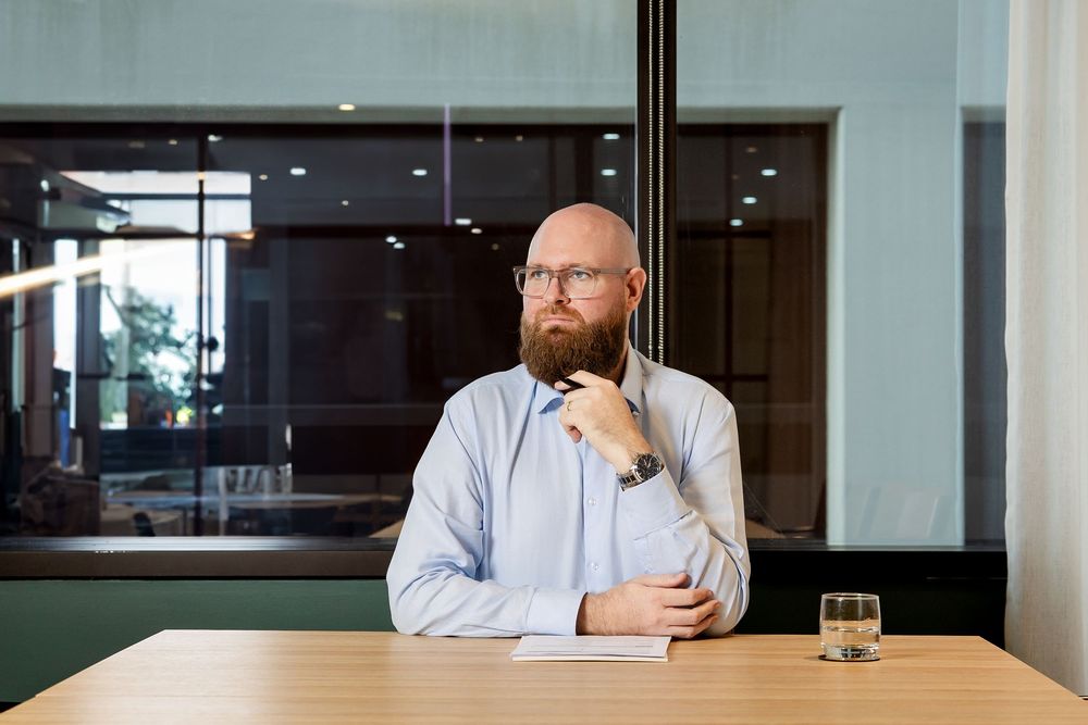 A person sits at a desk in a modern office space with glass walls and wood paneling.