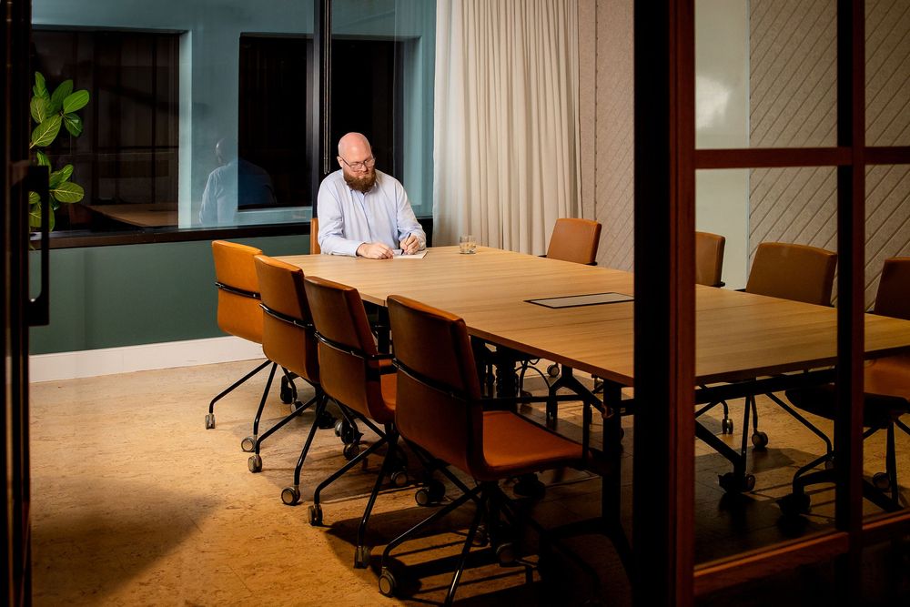 Modern office conference room with wooden table, chairs and glass walls in corporate setting.