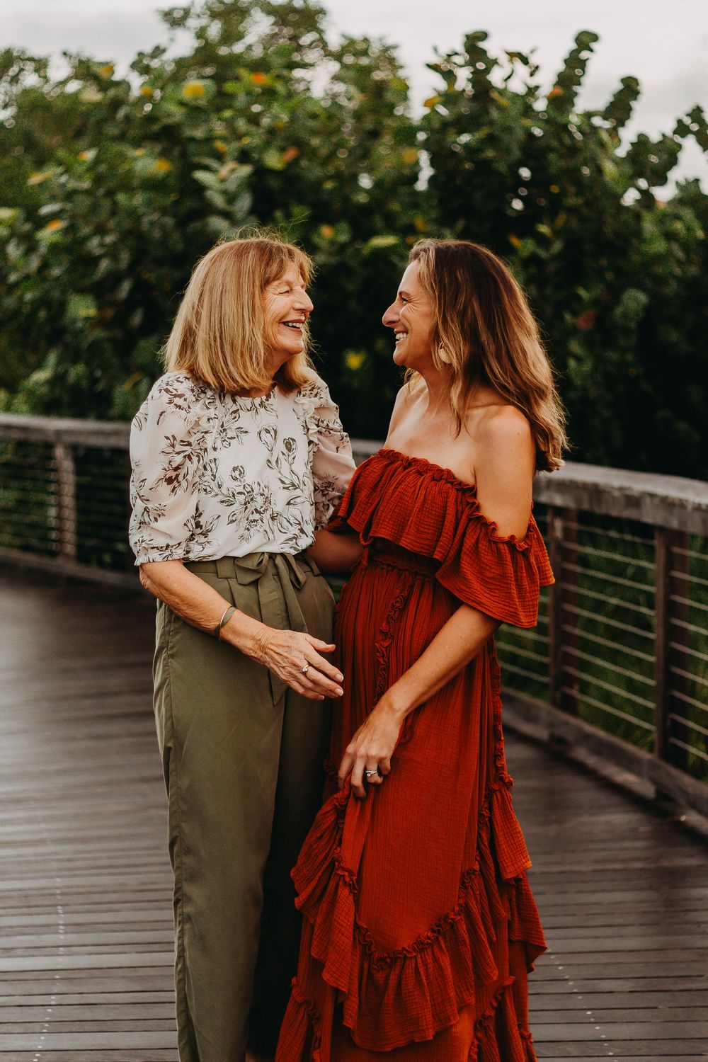 Family shares joyful moments together on a wooden bridge during sunset, wearing rustic autumn-colored clothing.