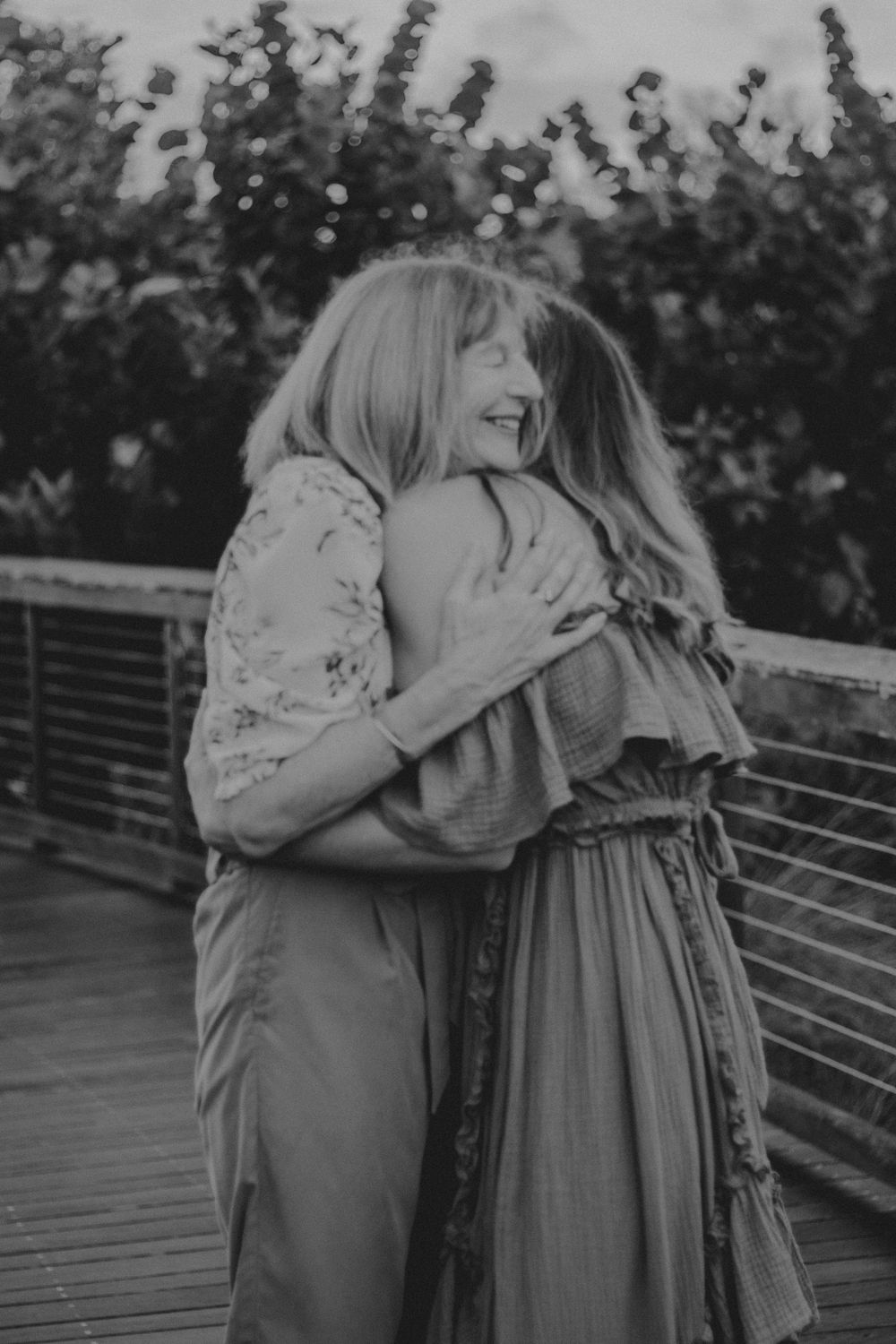 A couple embraces tenderly on a wooden deck with foliage in the background, shown in multiple similar poses.