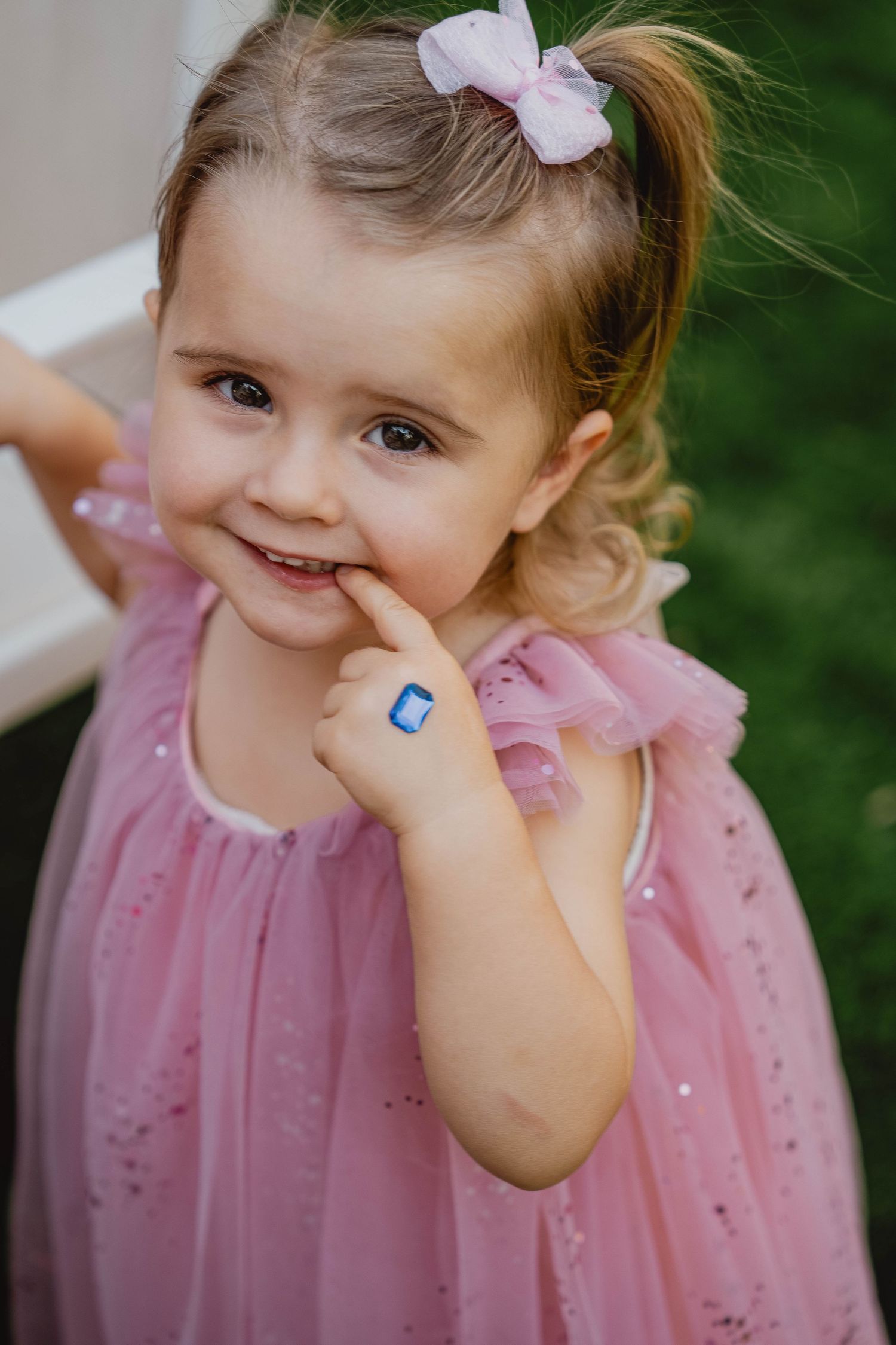 Young girl smiling in pink dress during outdoor family event