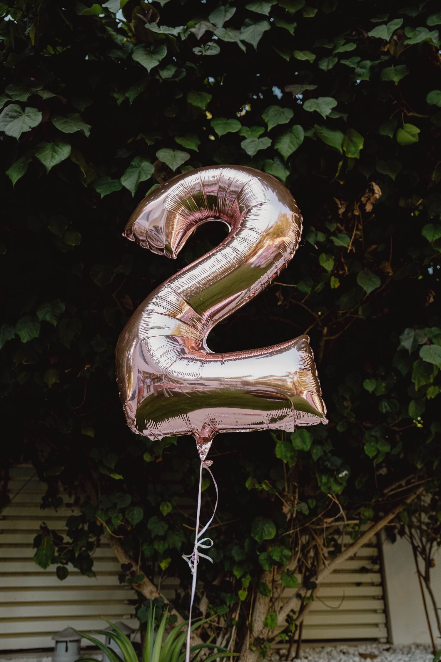 Rose gold number two balloon decoration at garden birthday setup