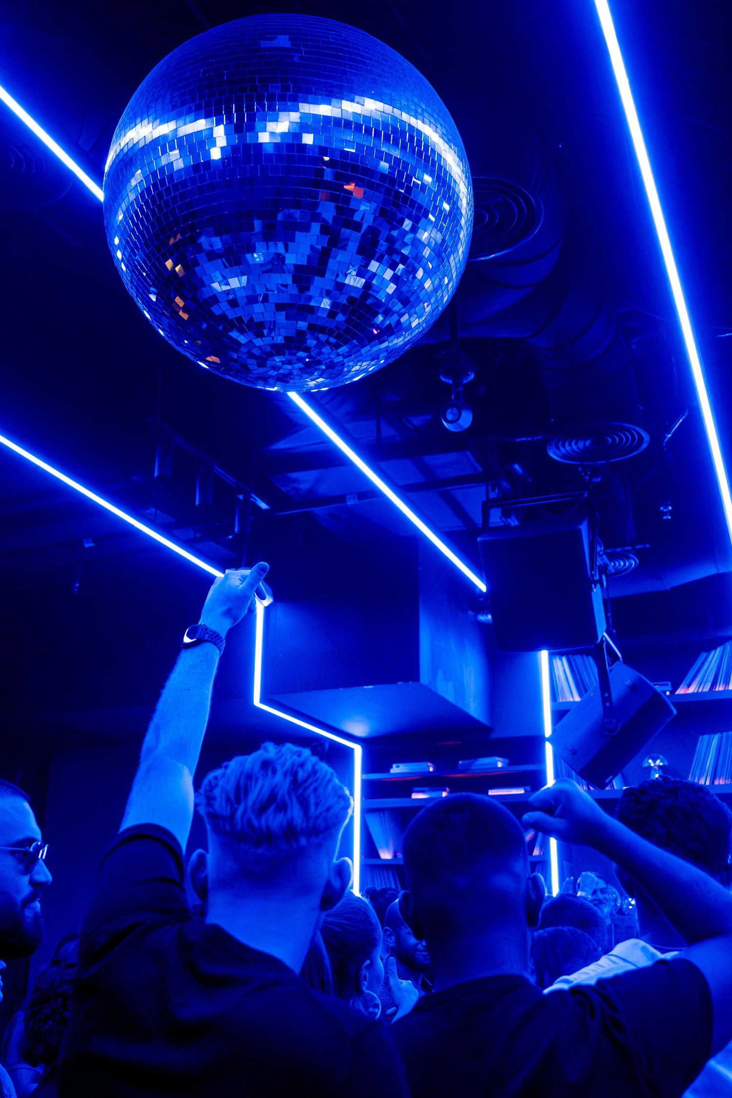 Disco ball reflecting blue lights over nightclub dance floor