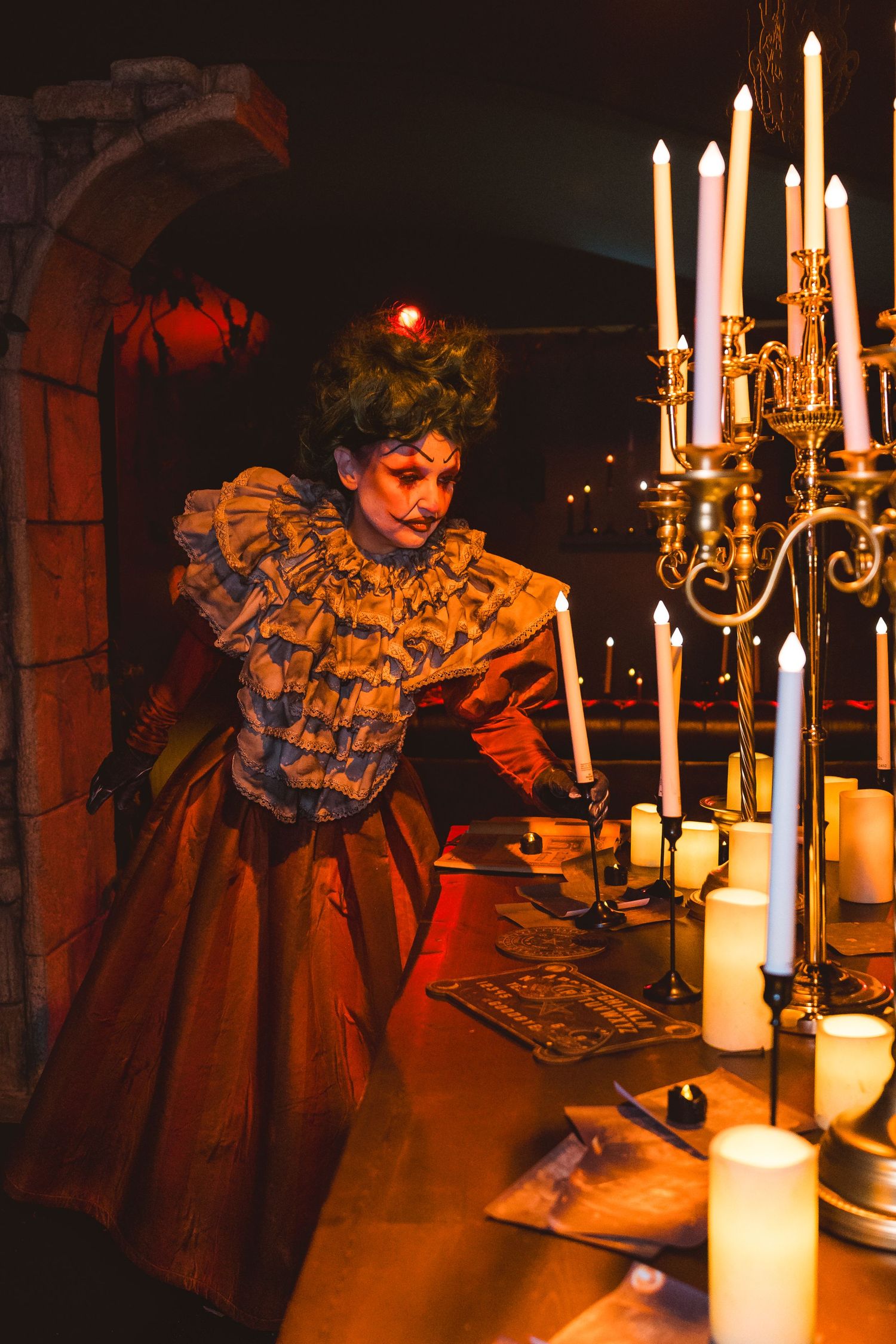 Costumed entertainer standing beside gothic candlelit decor