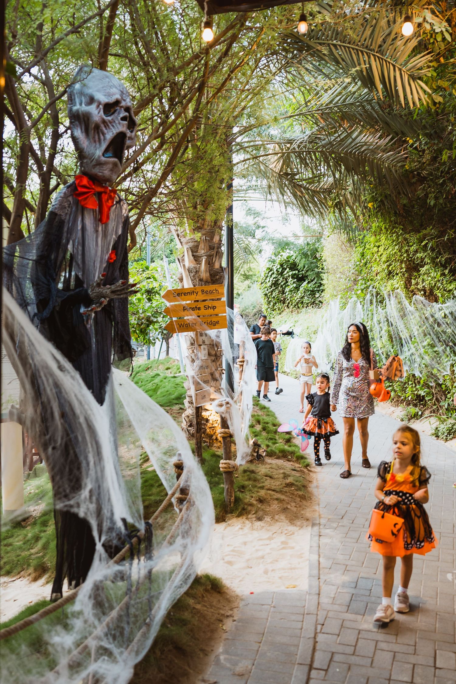 Families walking through decorated outdoor Halloween pathway