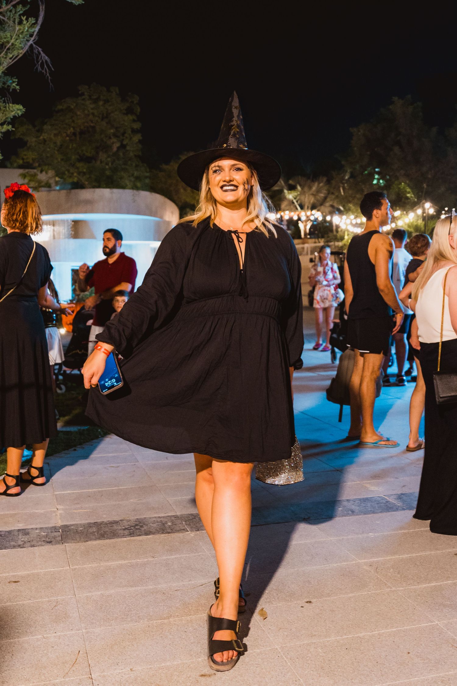 Woman in black outfit walking through evening outdoor festival