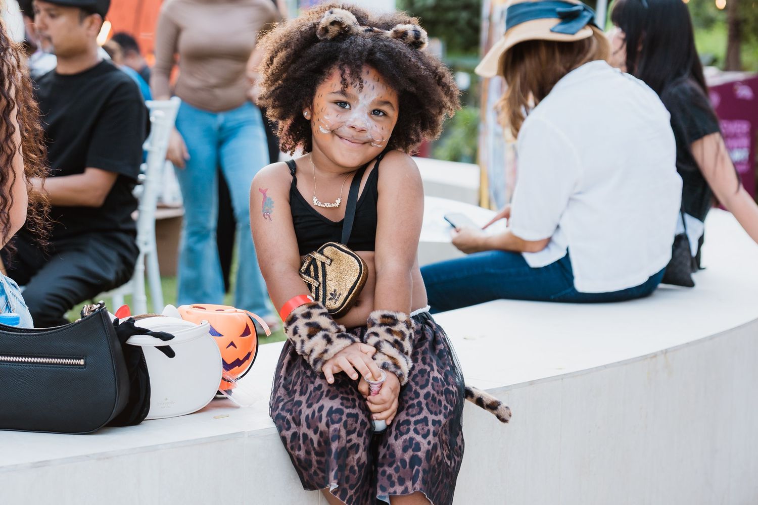 Young girl in Halloween costume sitting at outdoor community celebration