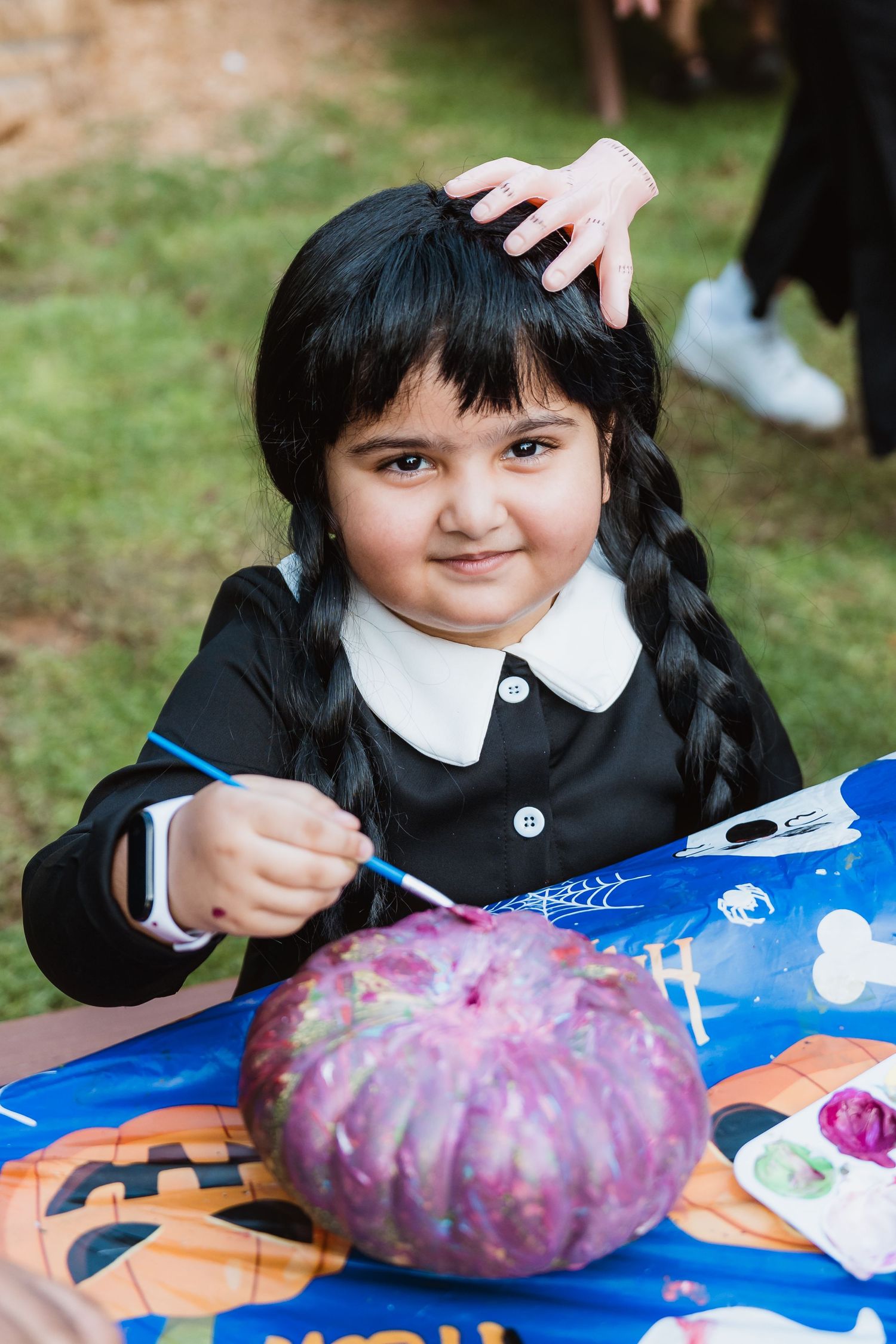 Young girl decorating pumpkin at outdoor craft station