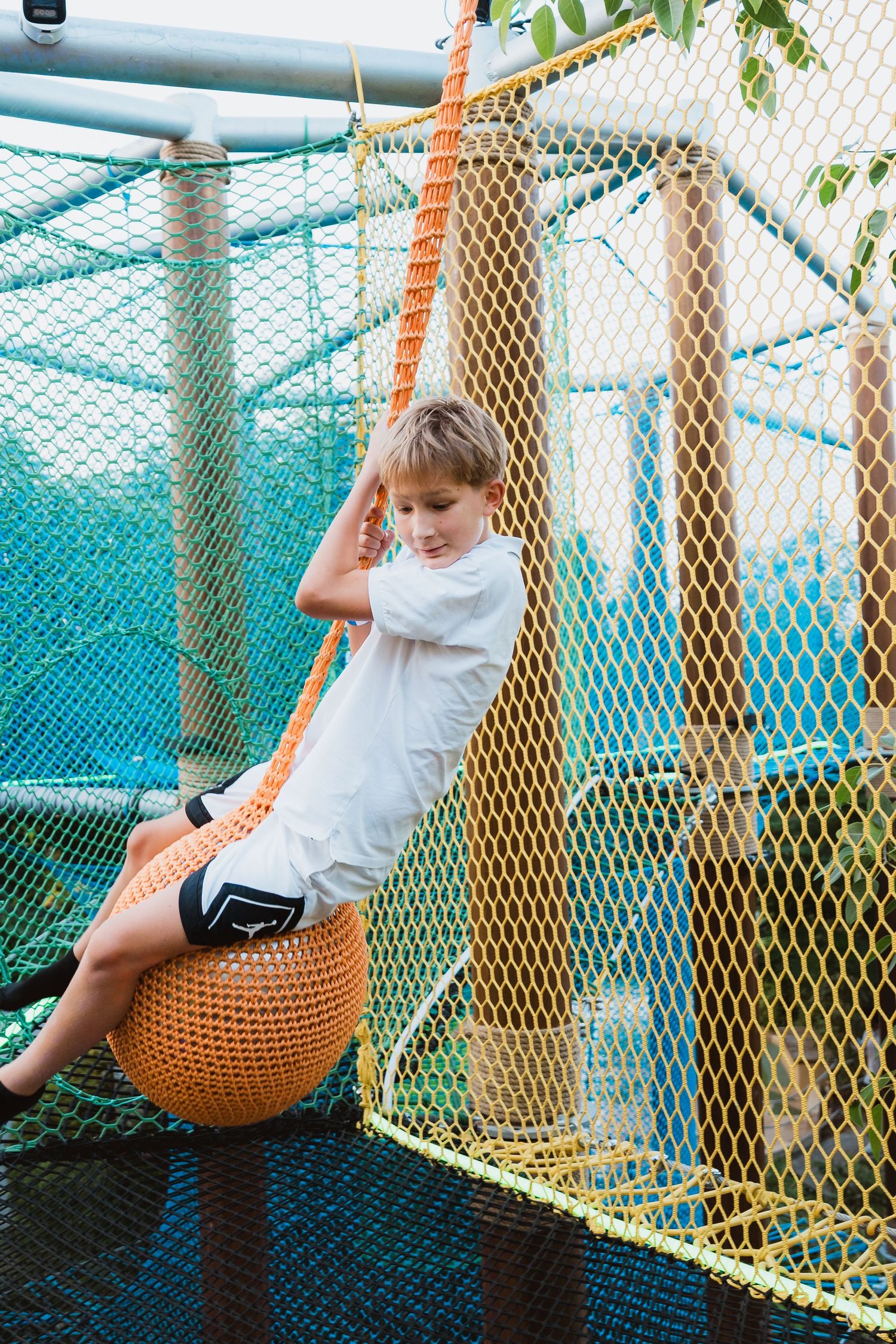 Young boy climbing rope bridge at community celebration