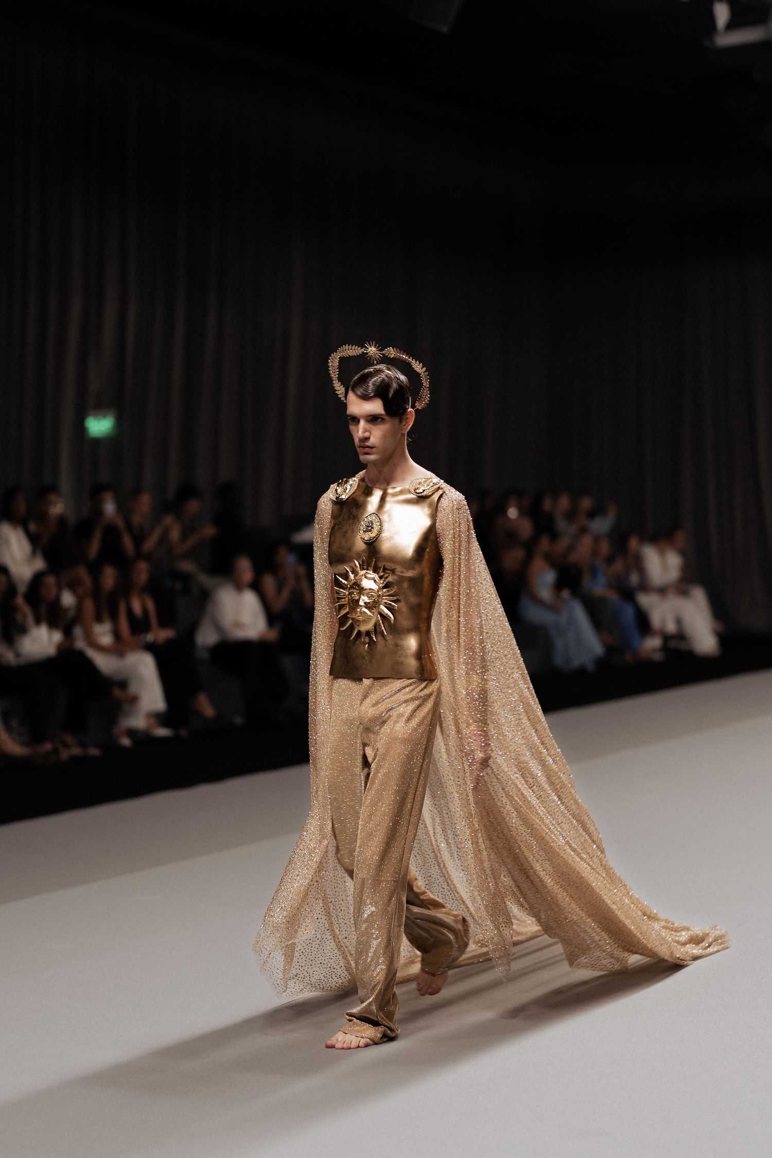 Runway model wearing elegant gold evening dress during fashion show in Dubai
