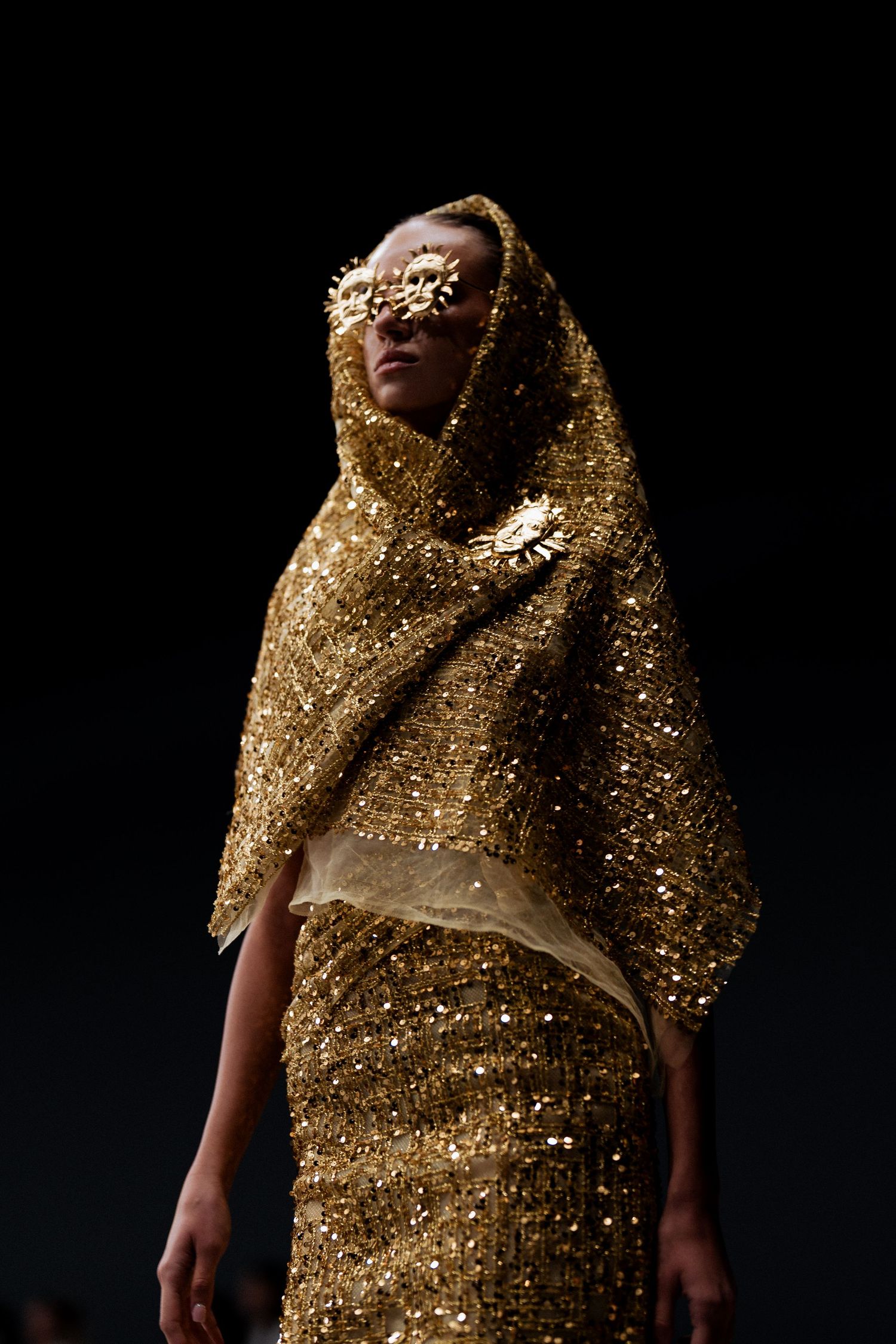 Model wearing gold hooded couture look at fashion show