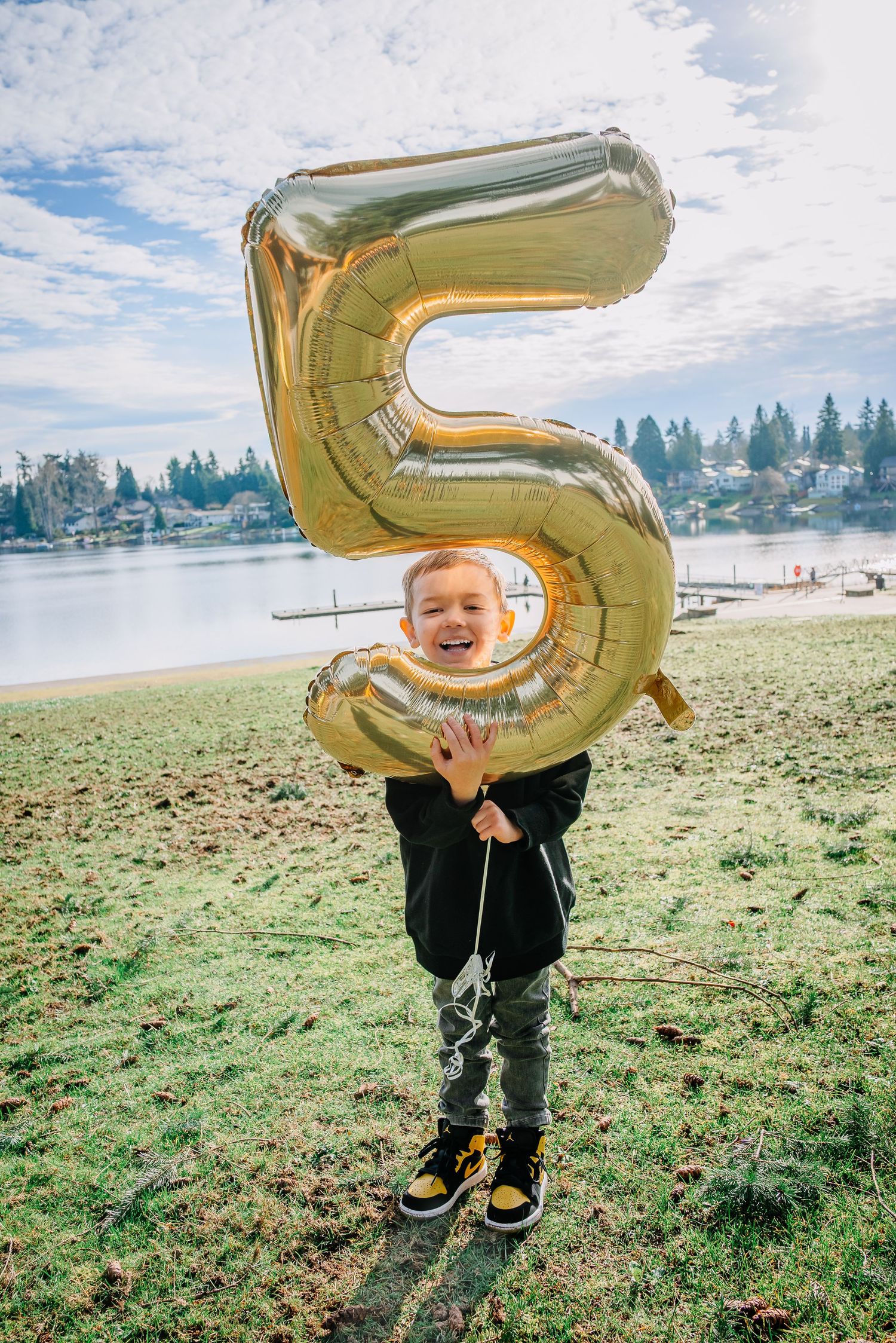 Five-year-old holding gold balloon during birthday family photos at Angel Lake Park