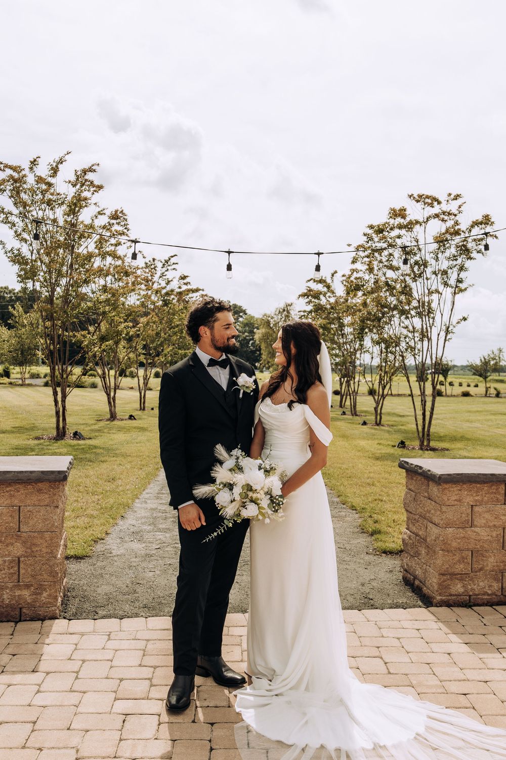 Bride and groom sharing a romantic moment on a brick pathway at an outdoor wedding venue.