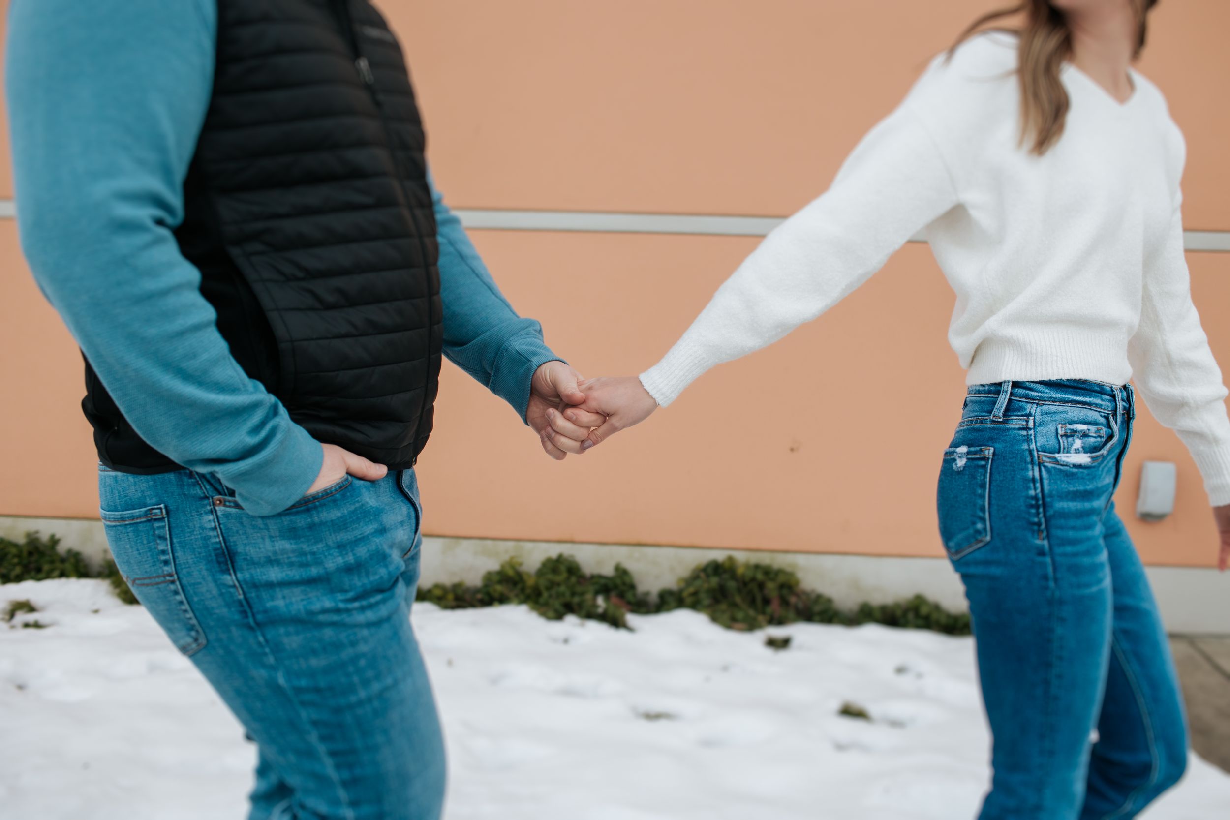 Romantic couple interacting against modern building exterior with snow on ground.