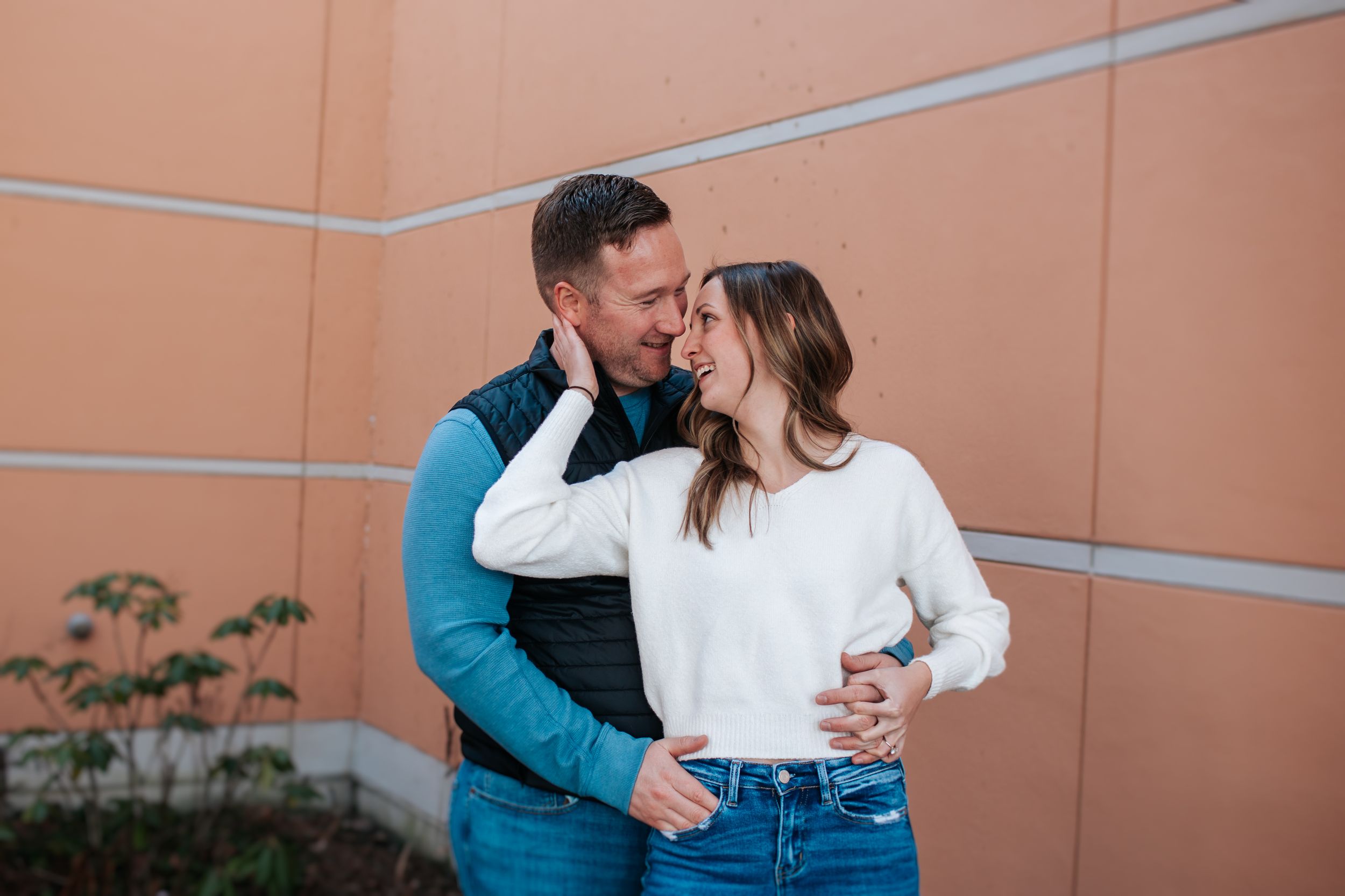 Intimate moment shared between couple against peachy wall background.