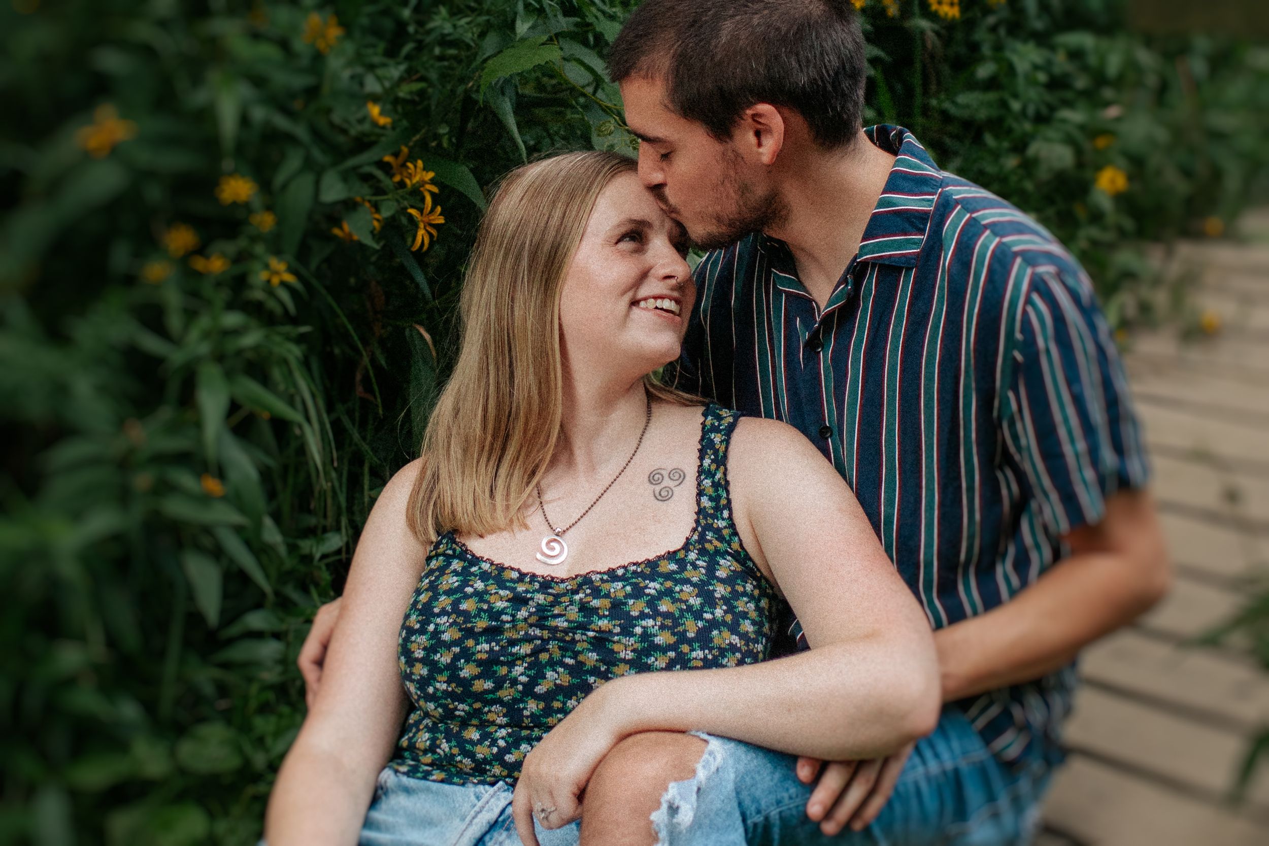 Couple shares tender moments together in a lush garden setting with yellow flowers in the background.