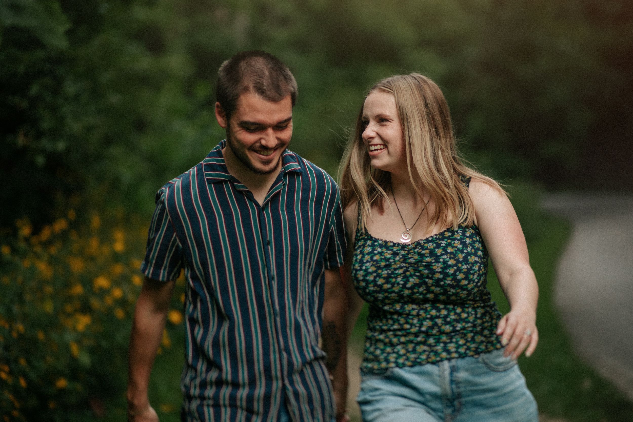 A couple laughing together while walking outdoors on a summer evening.