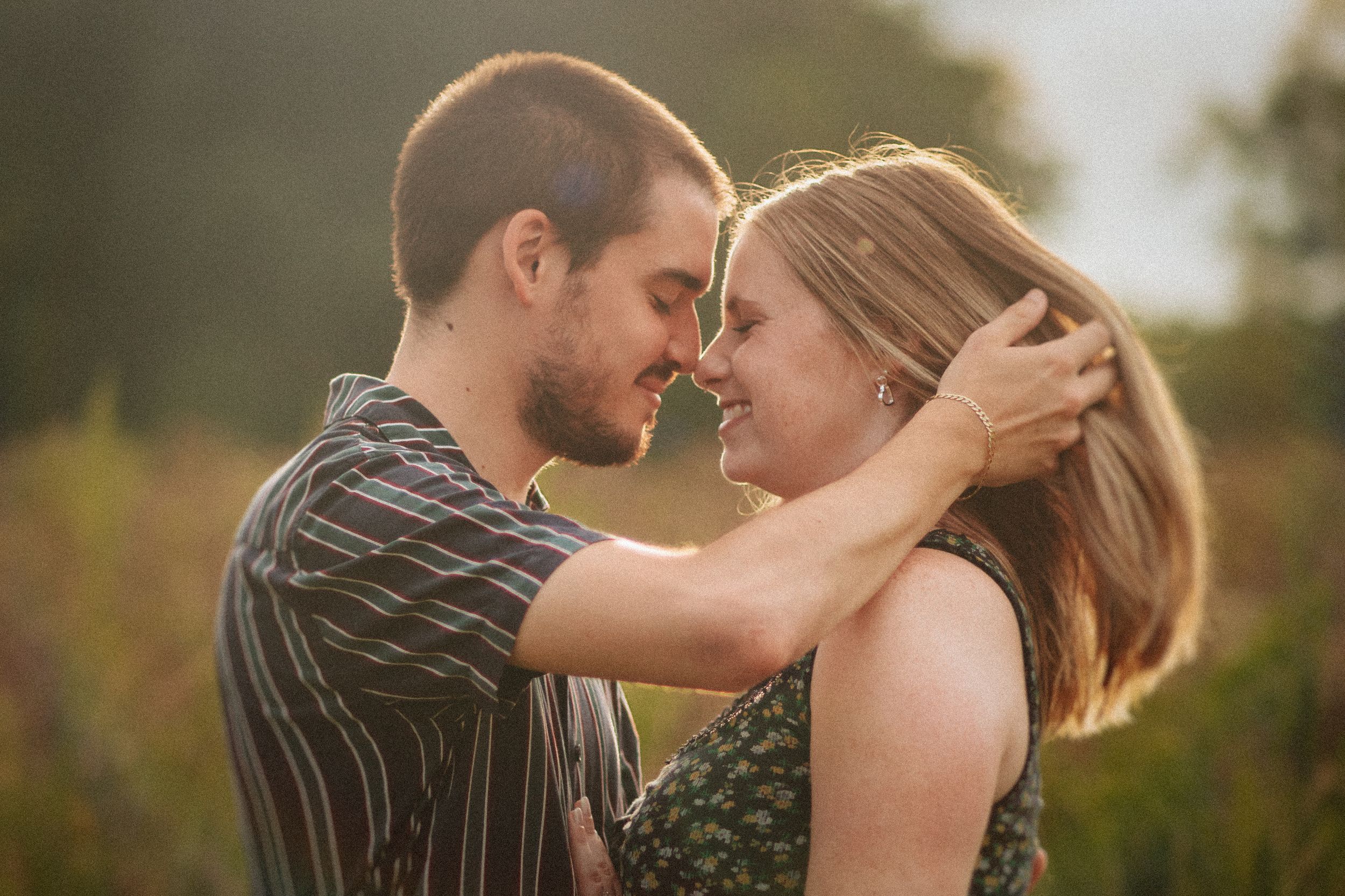 A romantic couple sharing an intimate moment together in a sunlit outdoor setting.