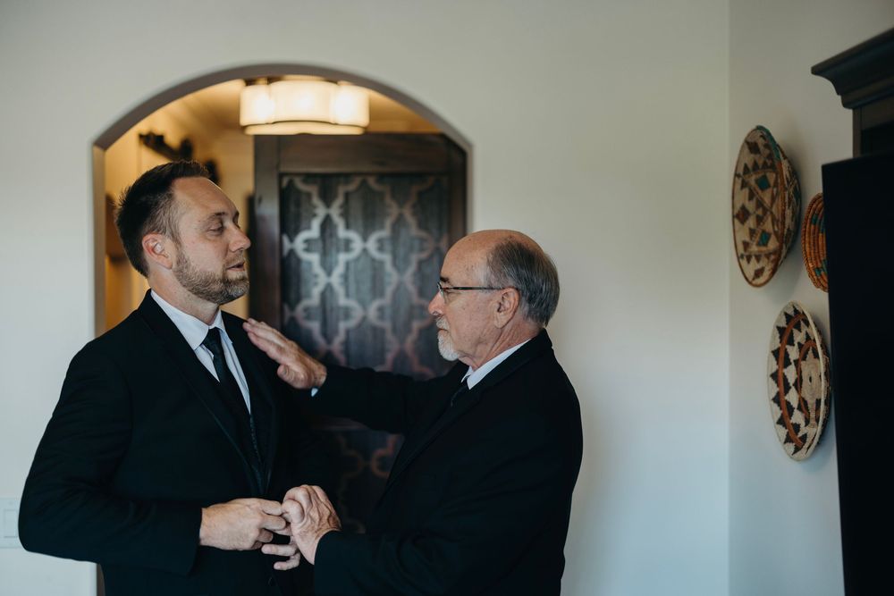 Wedding party members share intimate moments in a softly lit interior setting.