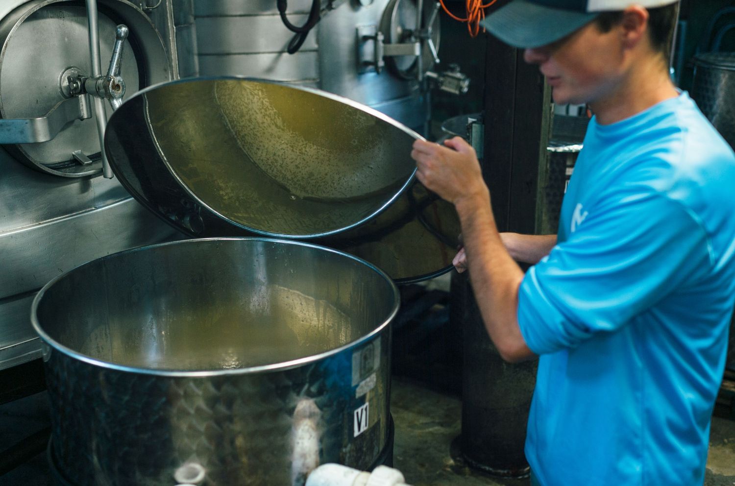 Large industrial cooking pots being prepared in a commercial kitchen.