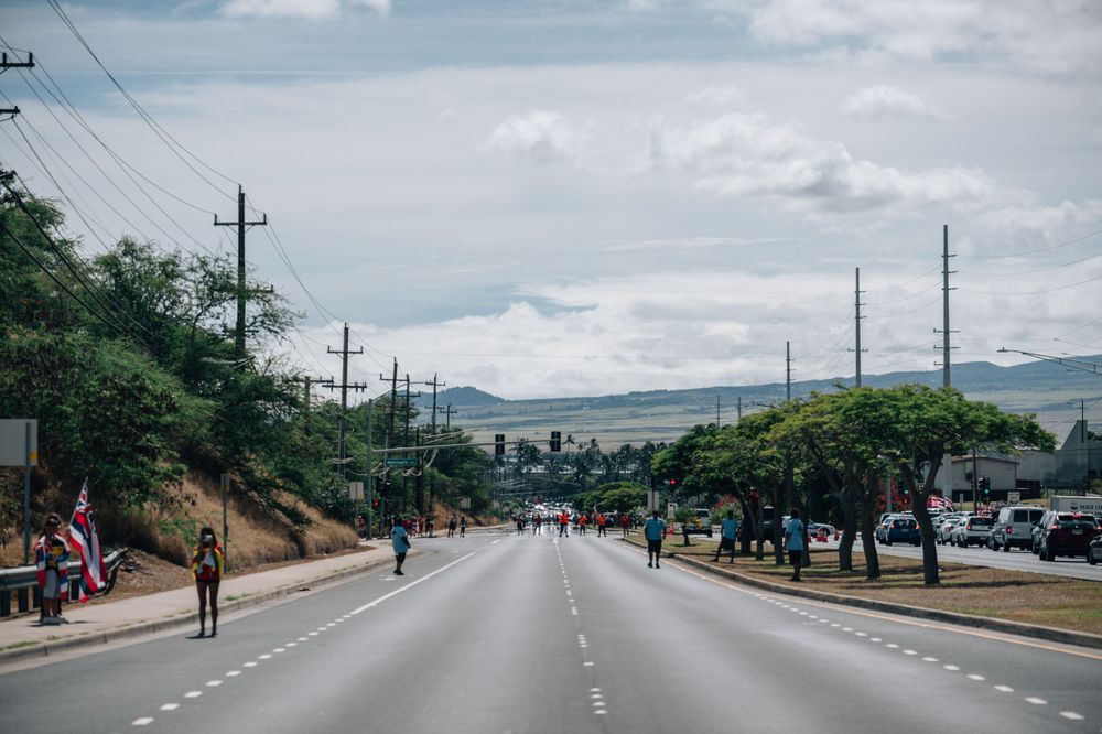 Empty highway stretches into the distance with utility poles and mountains visible in Hawaii.