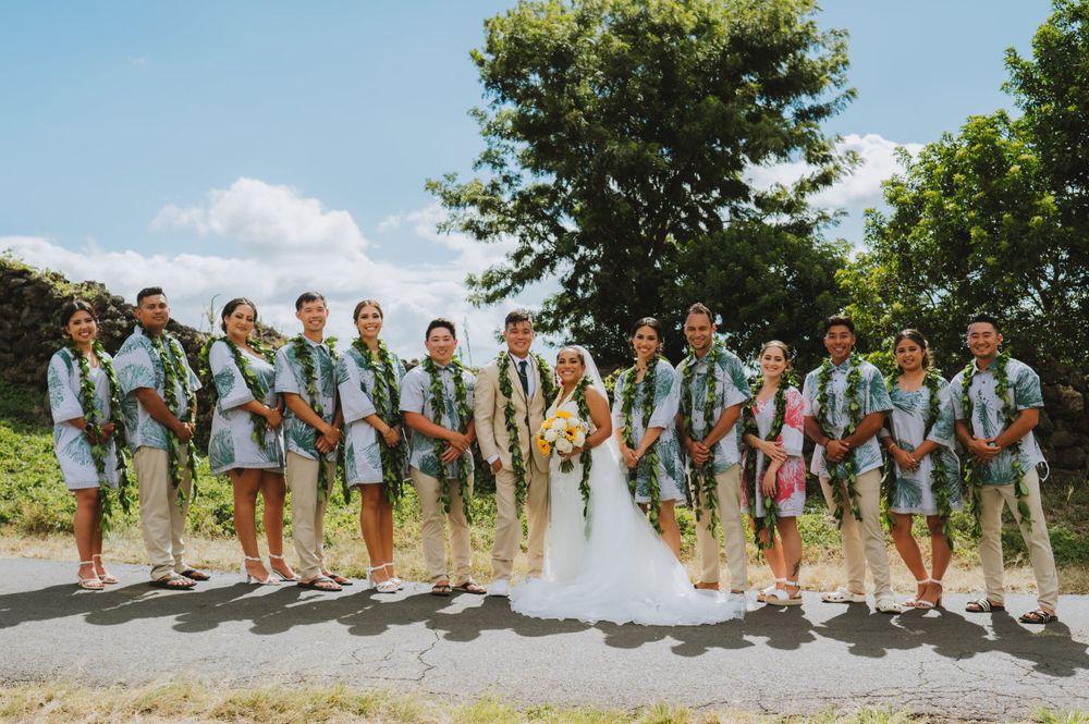 Wedding party lined up on mountain path wearing coordinated blue and white outfits.