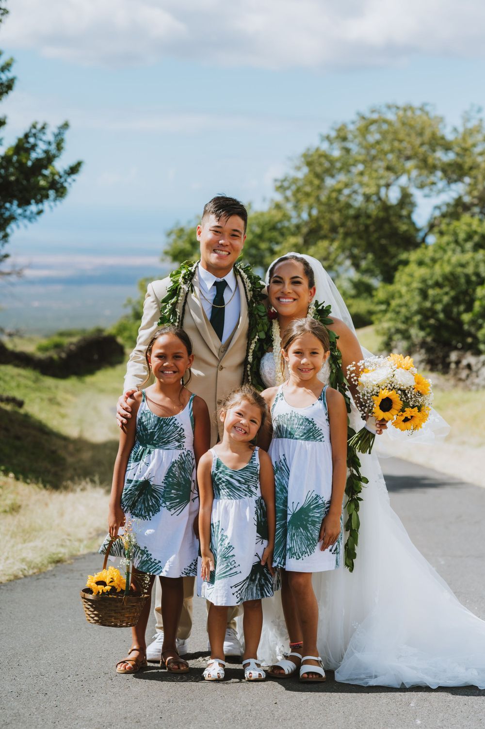 Wedding party in tropical print attire poses on scenic mountain road.