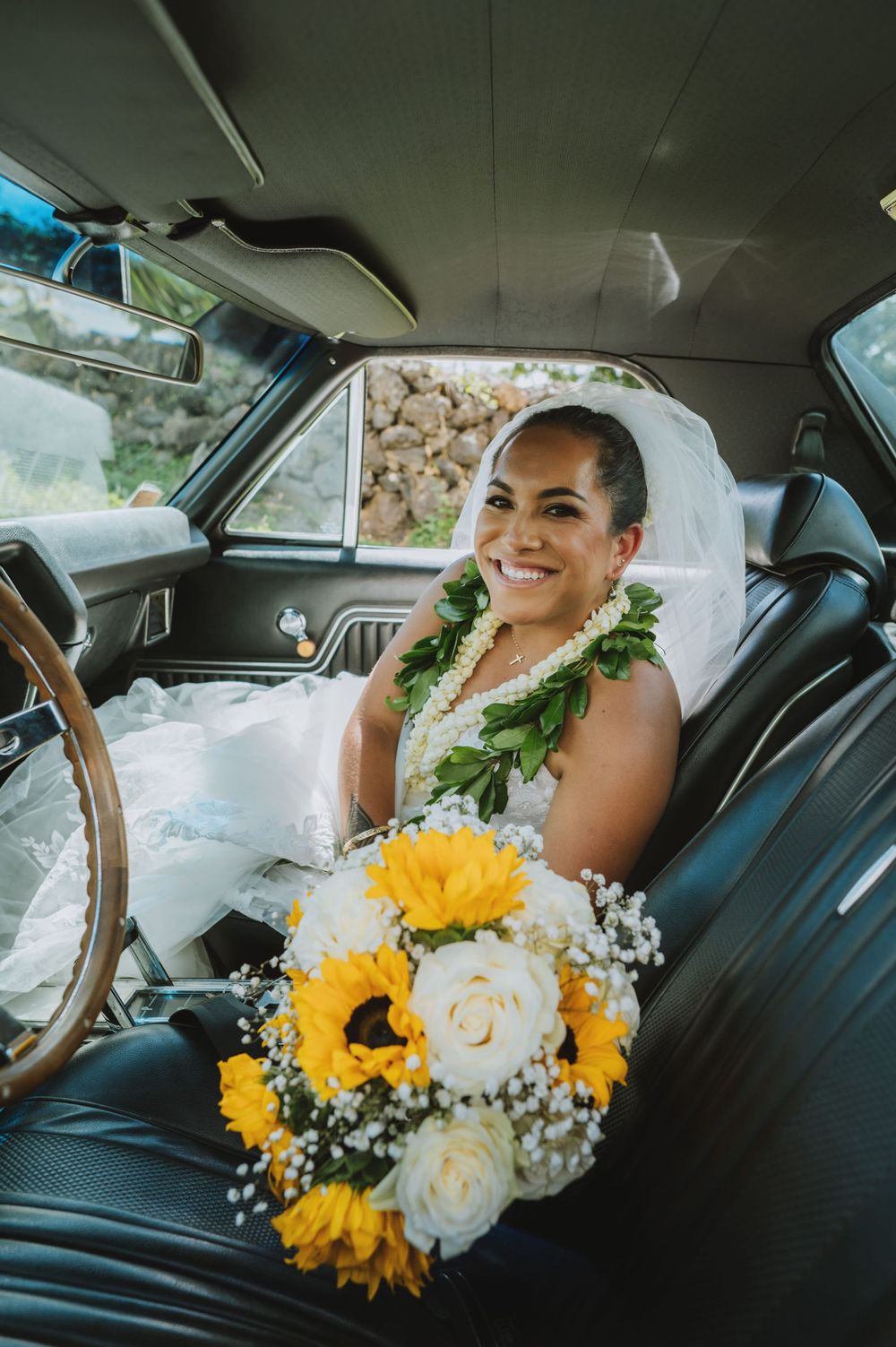 Elegant bridal portrait inside vintage car with yellow sunflowers and white flower bouquet.