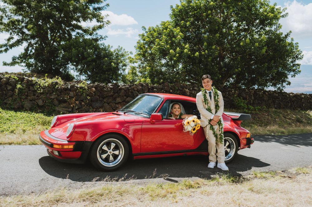 Classic red sports car parked on a scenic mountain road for wedding photos.