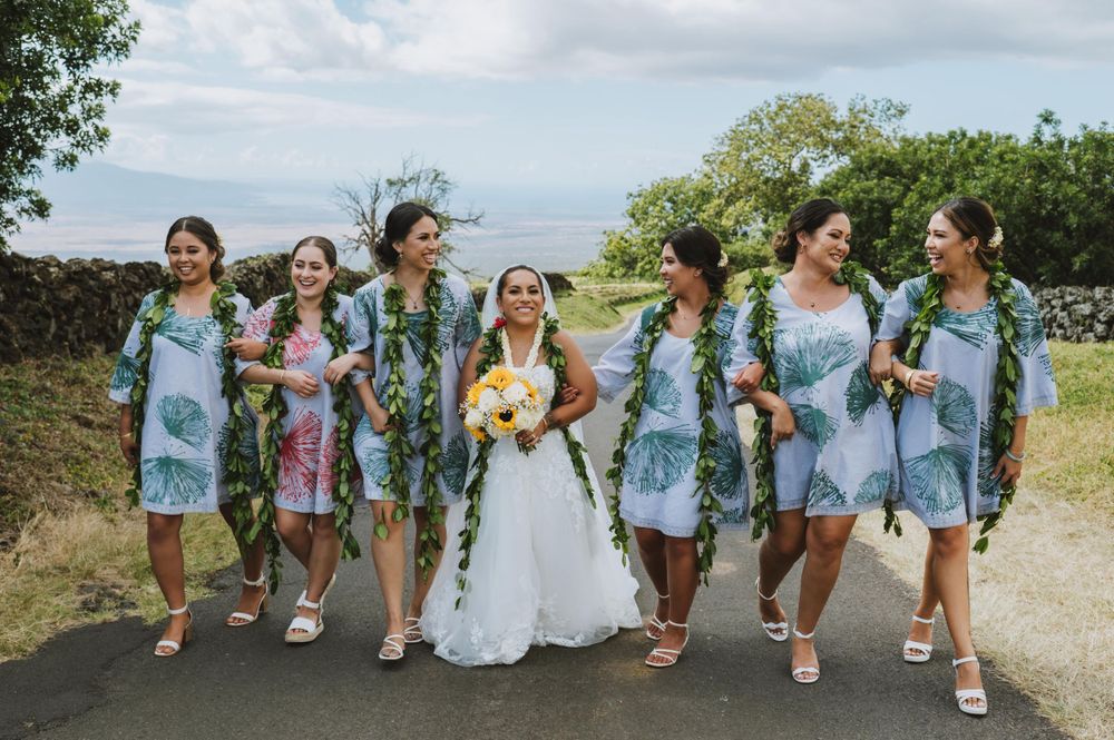 Bridesmaids in light blue dresses walking together on mountain path.