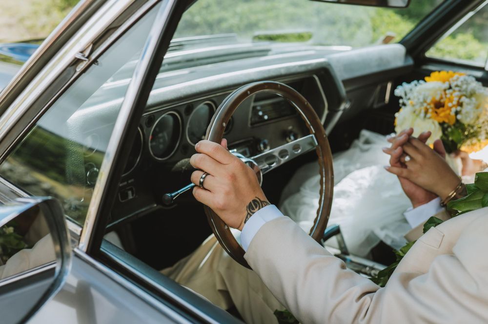 Wedding couple inside a classic car with sunflowers and white floral decorations.