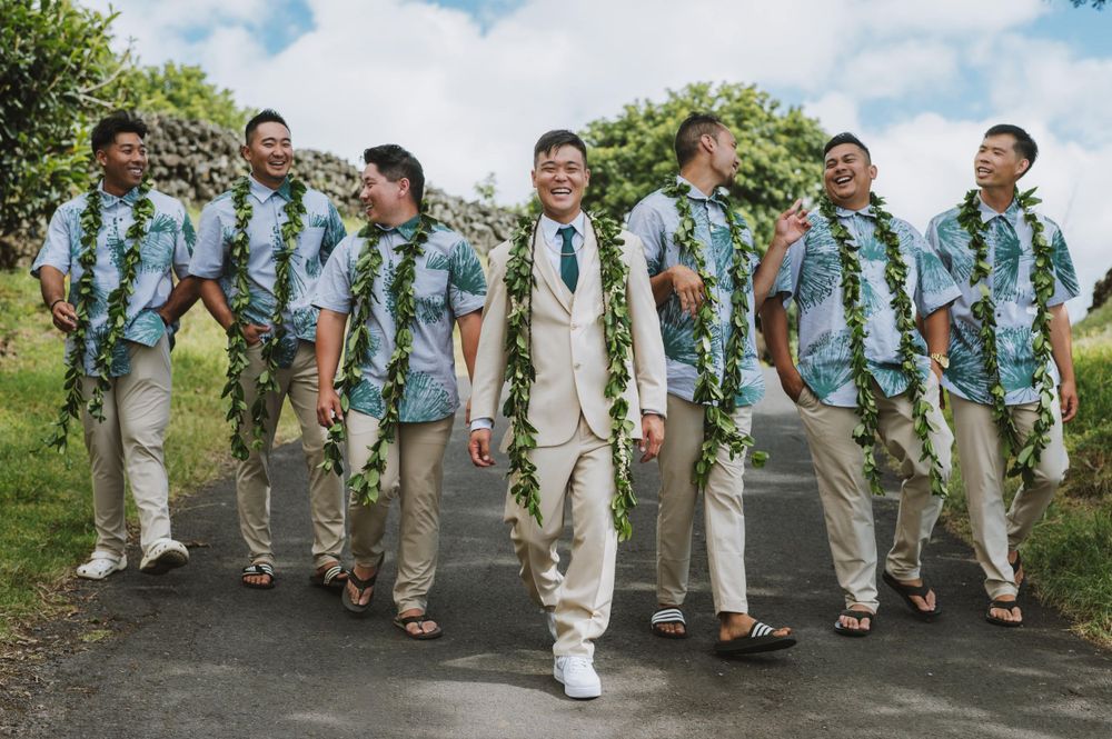 Wedding party wearing coordinated blue Hawaiian shirts and khaki pants walking together on a path.