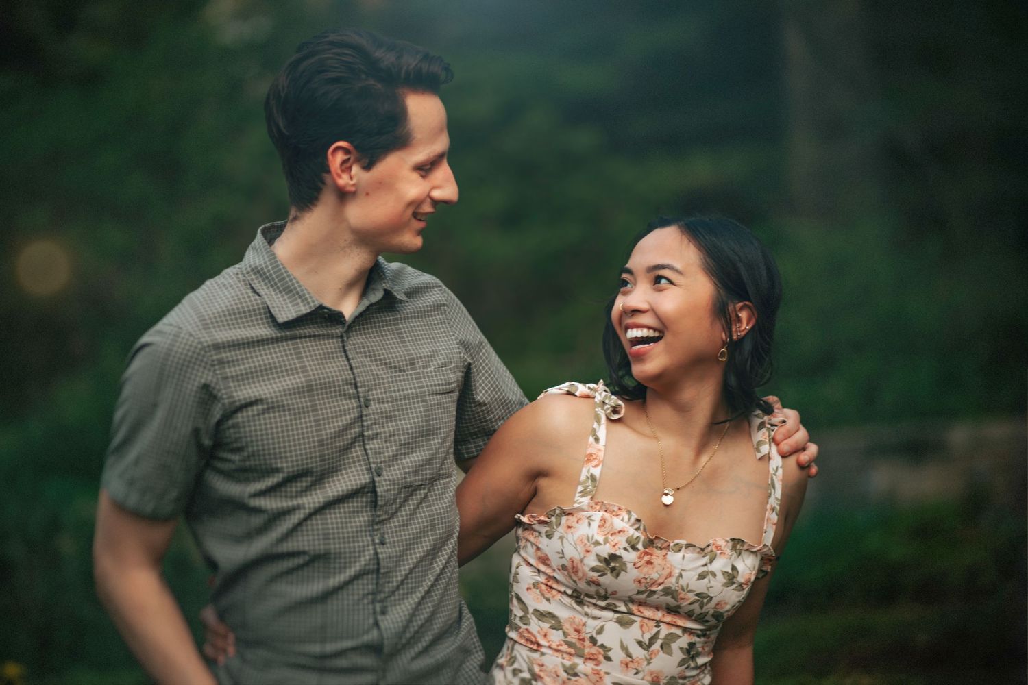 A couple shares joyful moments together outdoors while wearing casual attire and a floral dress.