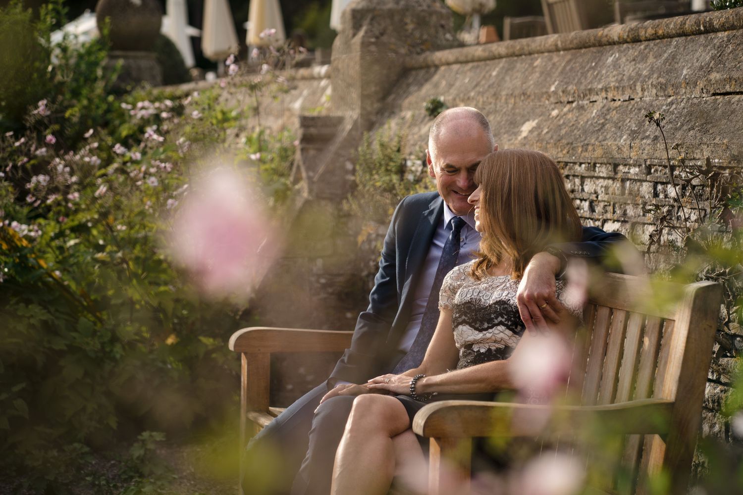 Documentary family photography with couple sitting together on a garden bench, photographed naturally during a relaxed outdoor family shoot.