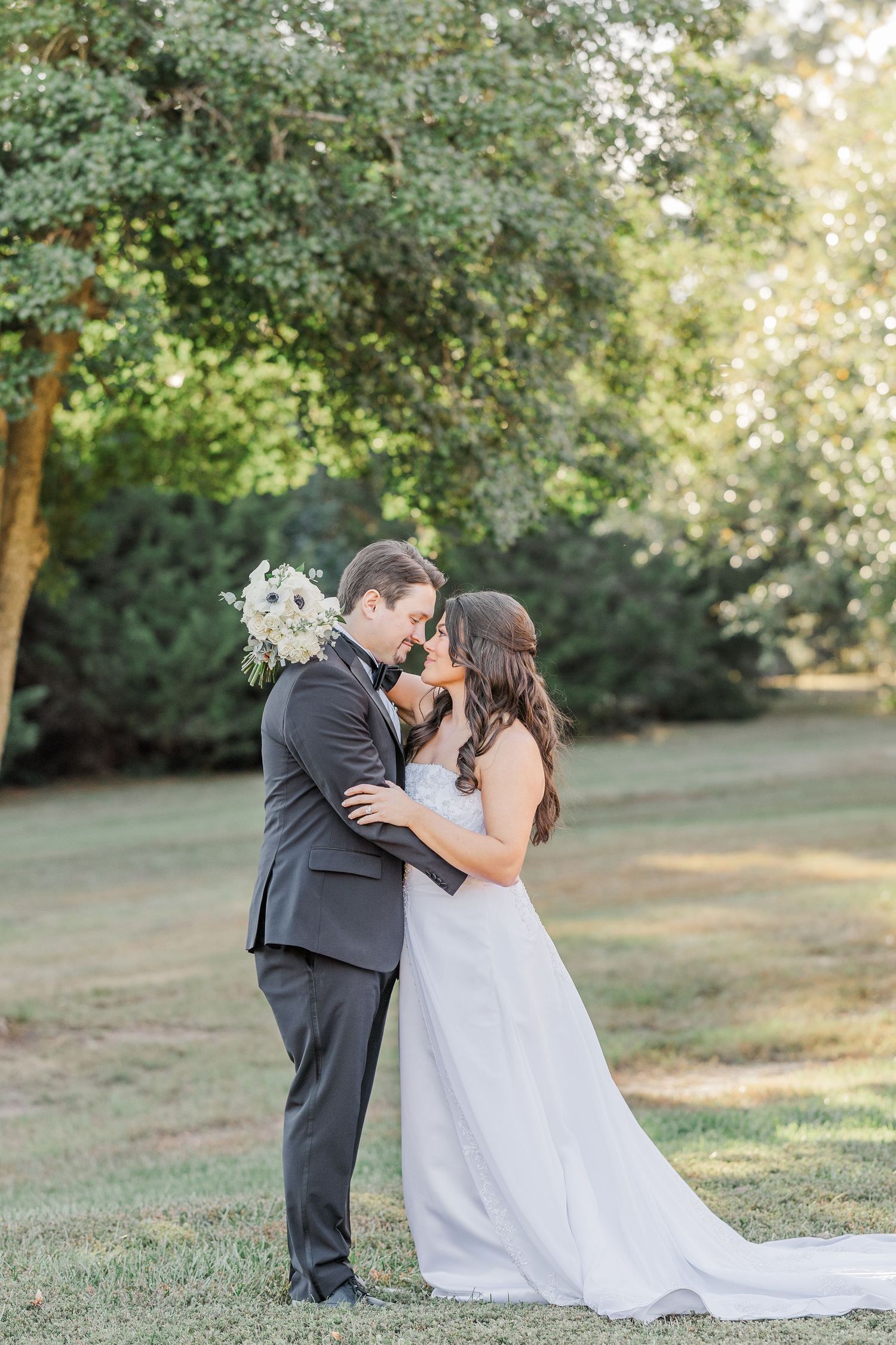 A romantic wedding couple shares tender kisses in a series of photos taken outdoors under blooming trees.