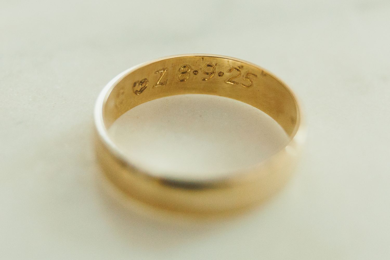 Close-up of a gold wedding band with engraved text inside.