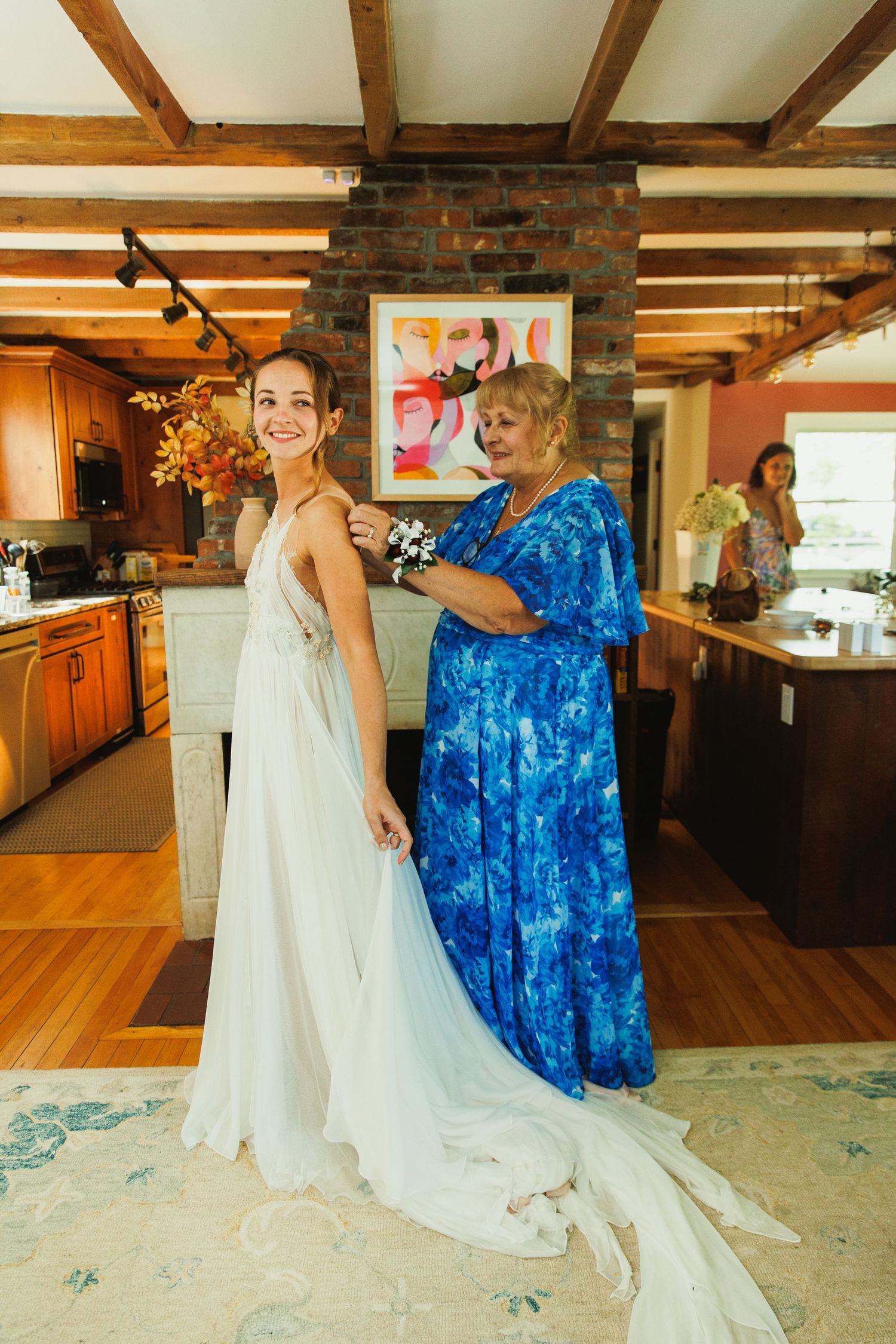A bride in a flowing white gown shares a joyful moment with someone in a bright blue dress on a hardwood floor.