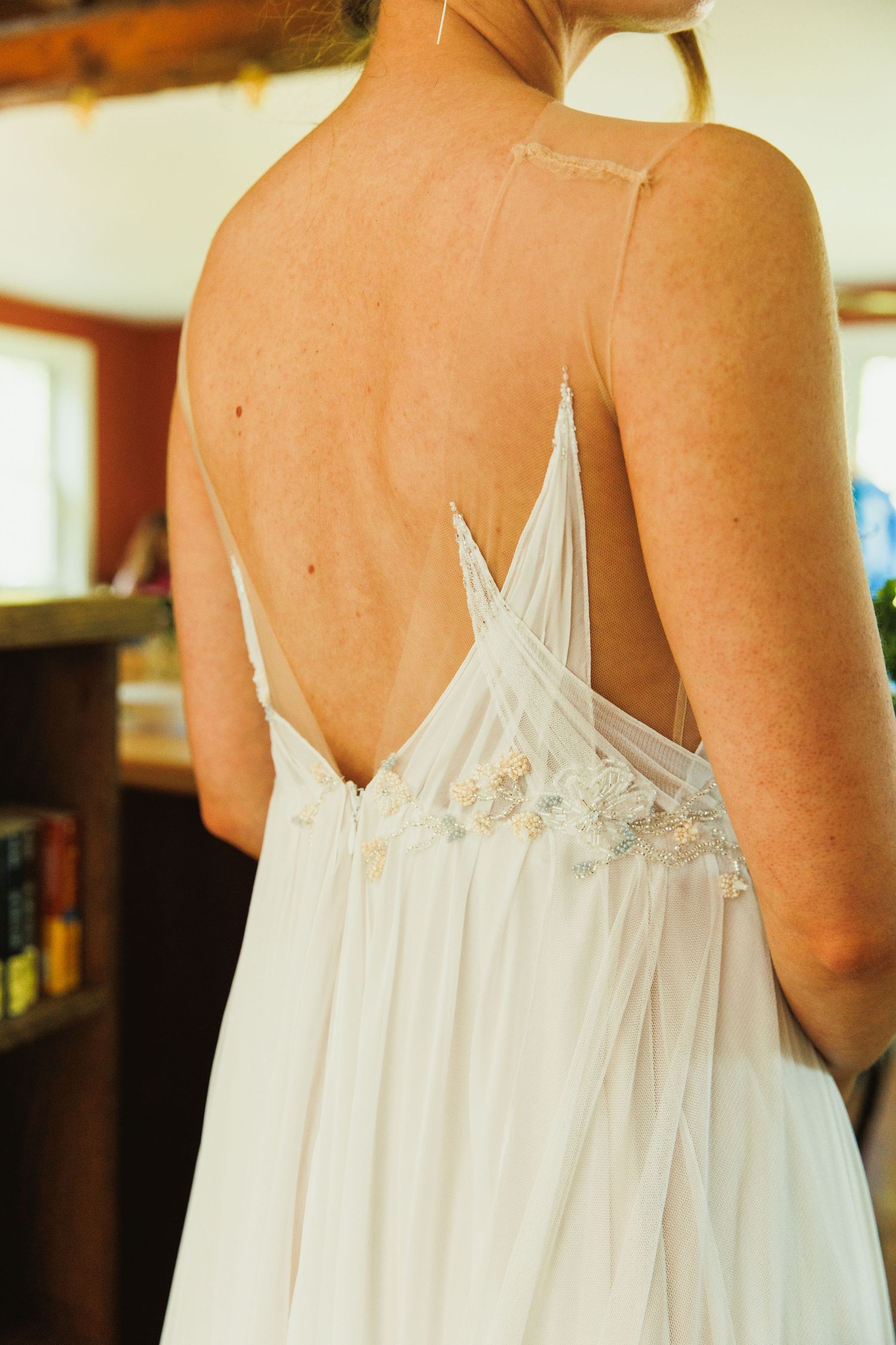 Back detail of a white wedding dress showing delicate lace straps and flowing fabric.