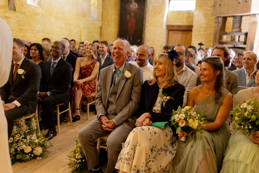 Wedding guests seated in rows watching a ceremony in a rustic stone-walled venue.