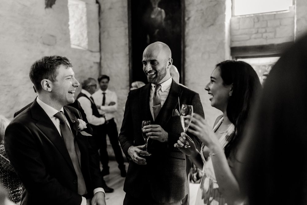 Wedding guests share joyful laughter and conversation during an intimate indoor reception celebration.