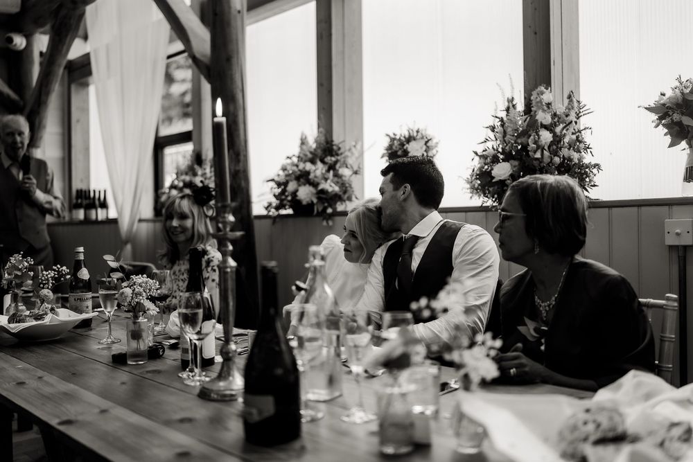 Black and white photograph of an elegant indoor reception setup with floral centerpieces.