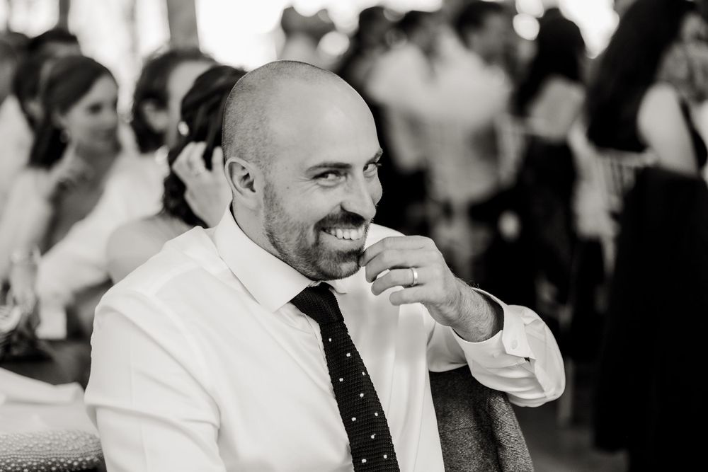 Black and white portrait of a guest smiling during a wedding reception.
